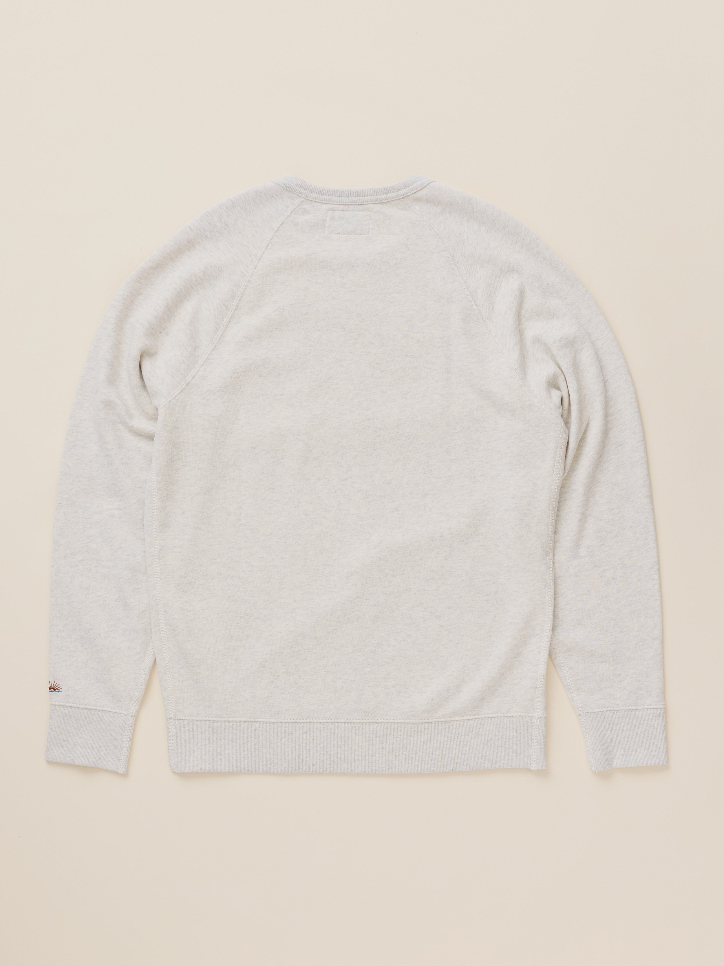 A light heather gray crewneck sweatshirt shown from the back, laid flat on a warm beige background.