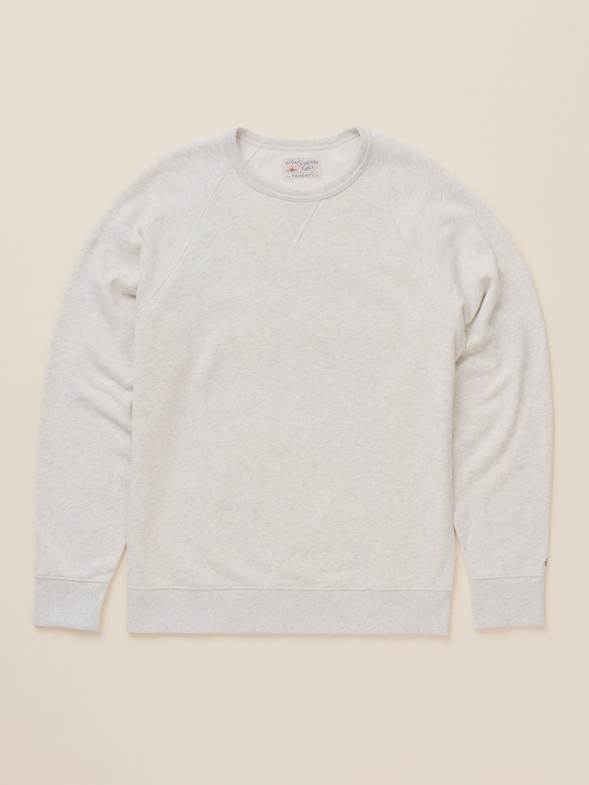 A light heather gray crewneck sweatshirt laid flat against a solid cream-colored background.