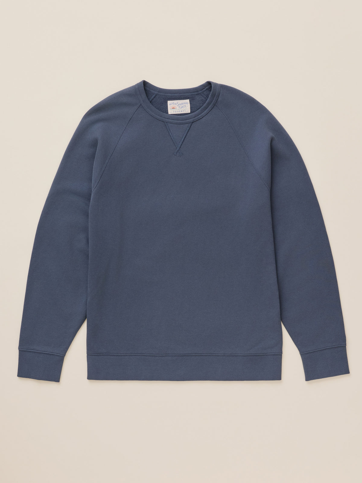 A slate blue crewneck sweatshirt with raglan sleeves, laid flat against a solid beige background., image 1 of 2