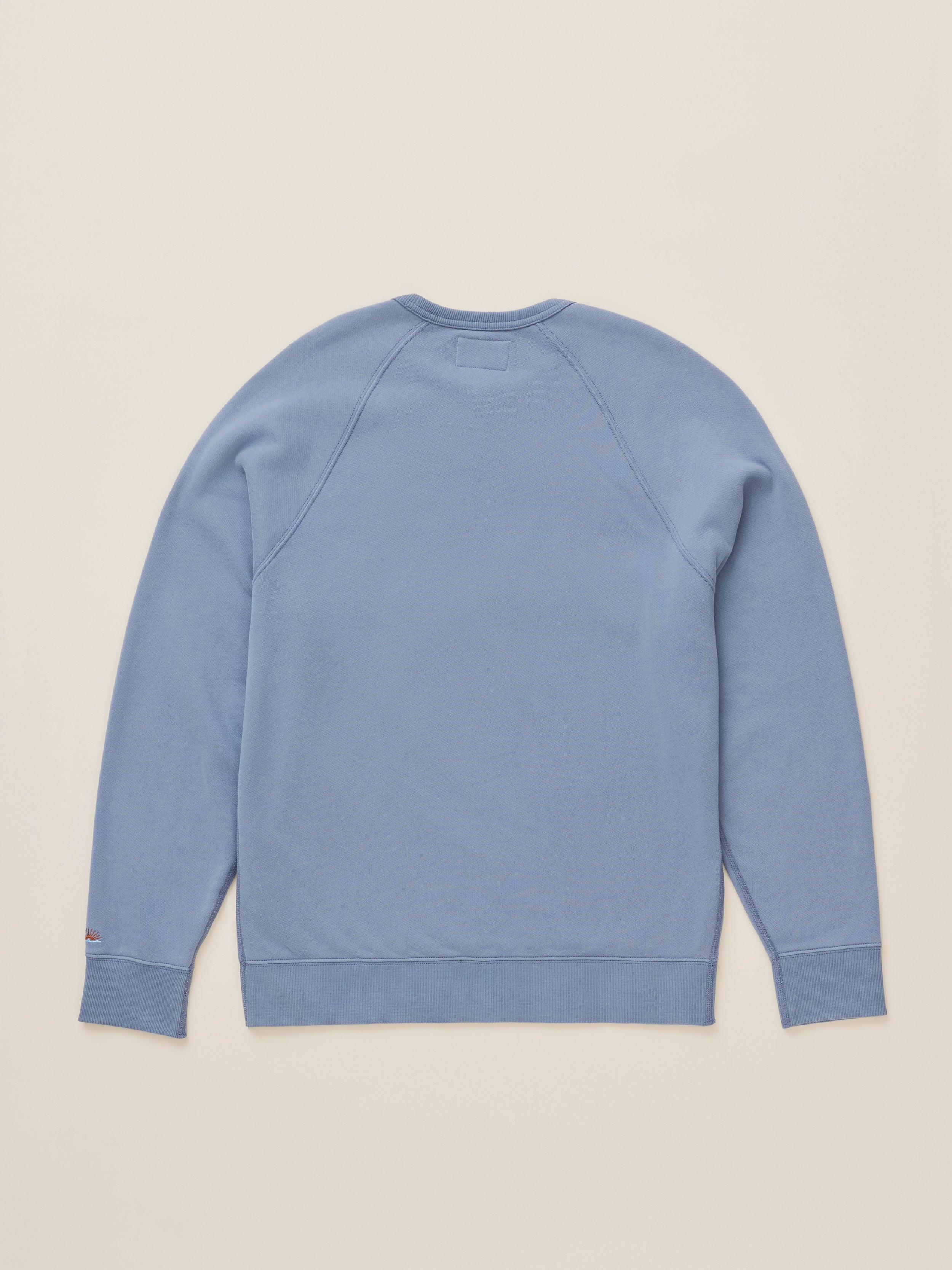 A light blue crewneck sweatshirt shown from the back, laid flat on a solid beige background.