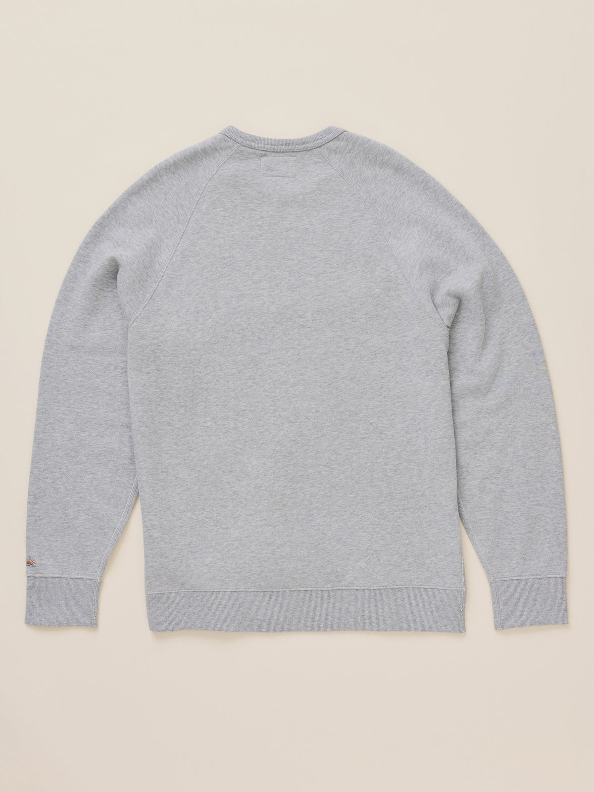 A light gray heather crewneck sweatshirt shown from the back, laid flat on a warm beige background., image 2 of 2