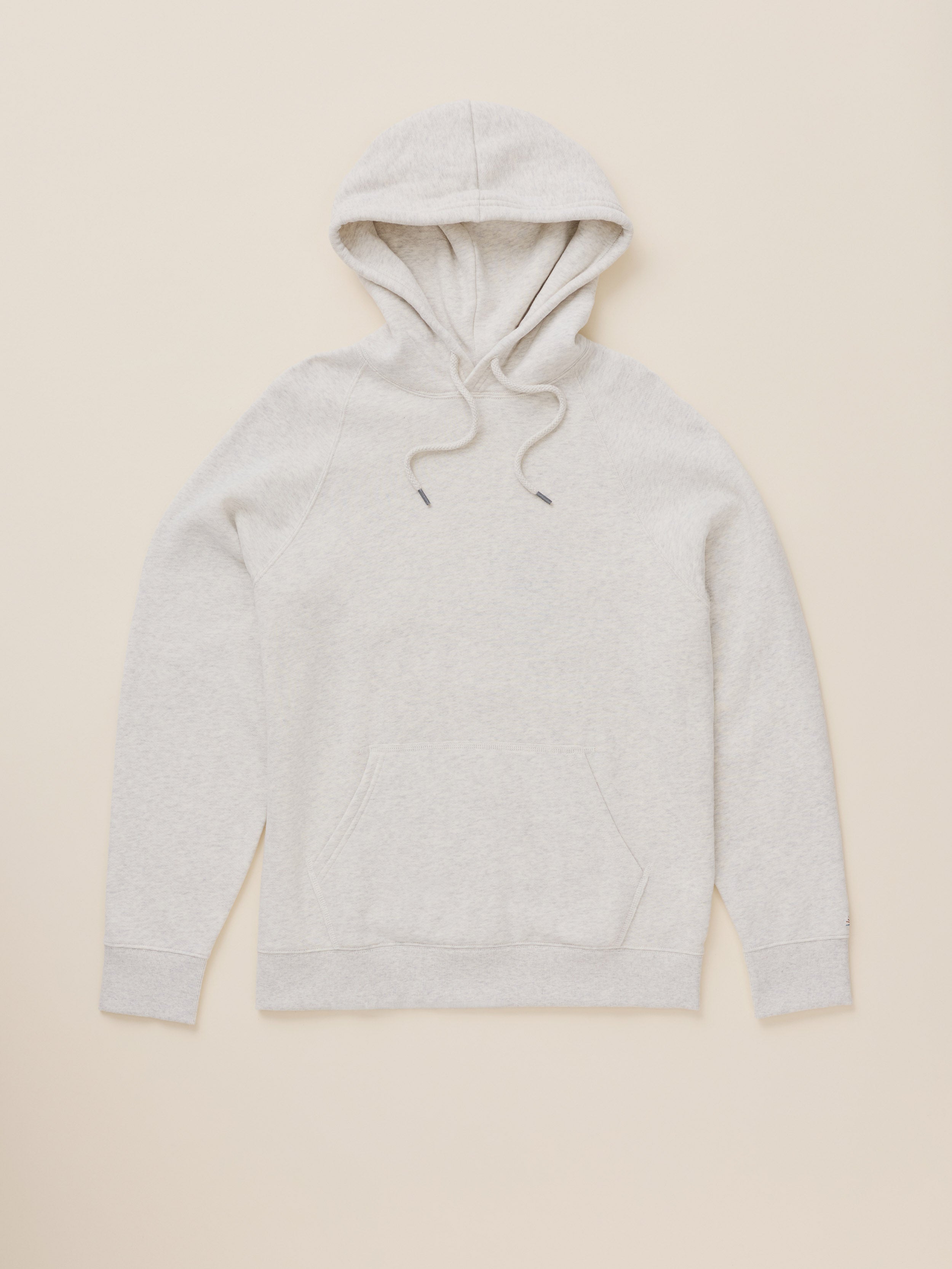 A light heather gray pullover hoodie with matching drawstrings, laid flat against a solid beige background.