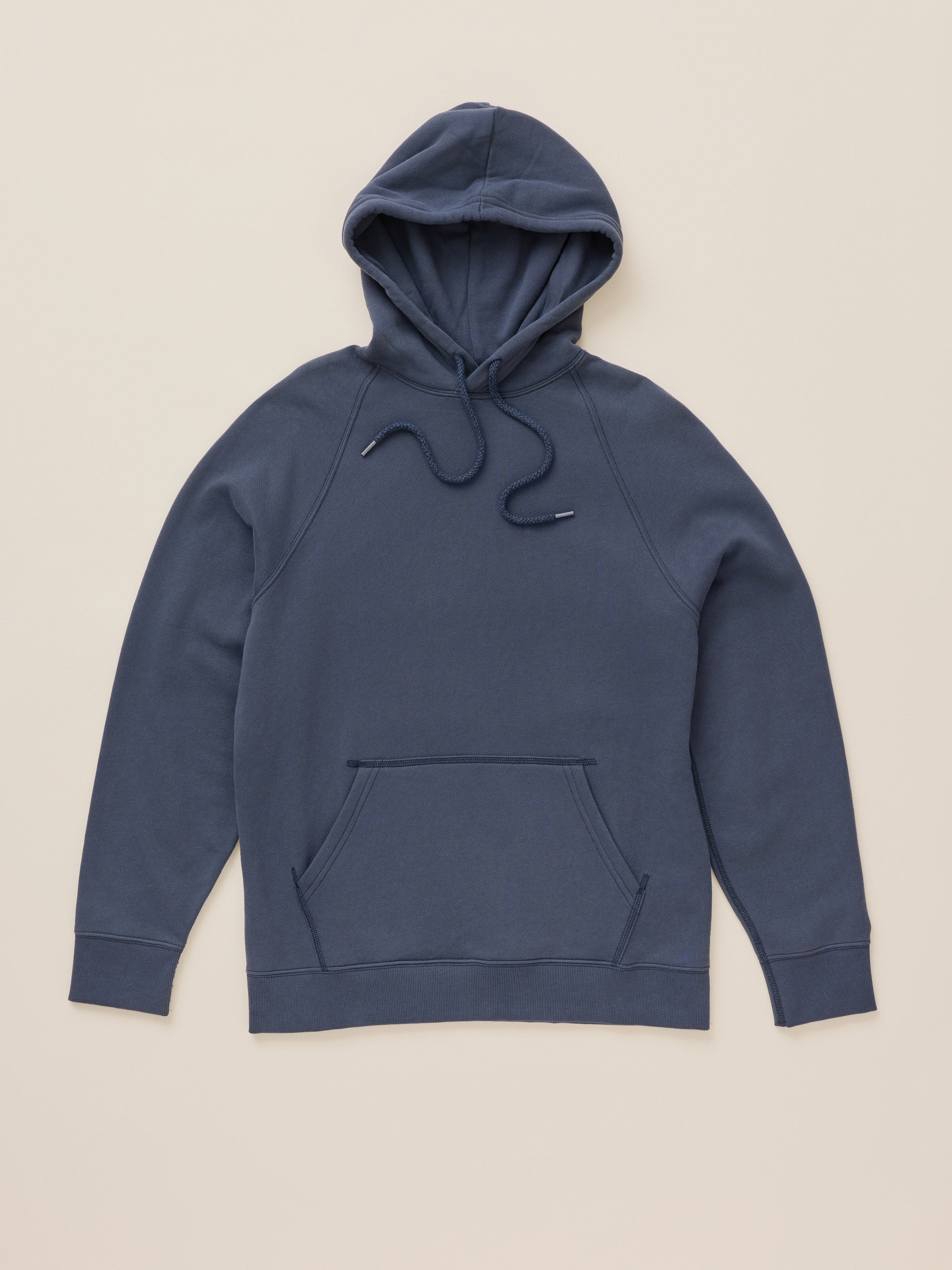 A navy blue pullover hoodie with matching drawstrings, laid flat against a solid light beige background.