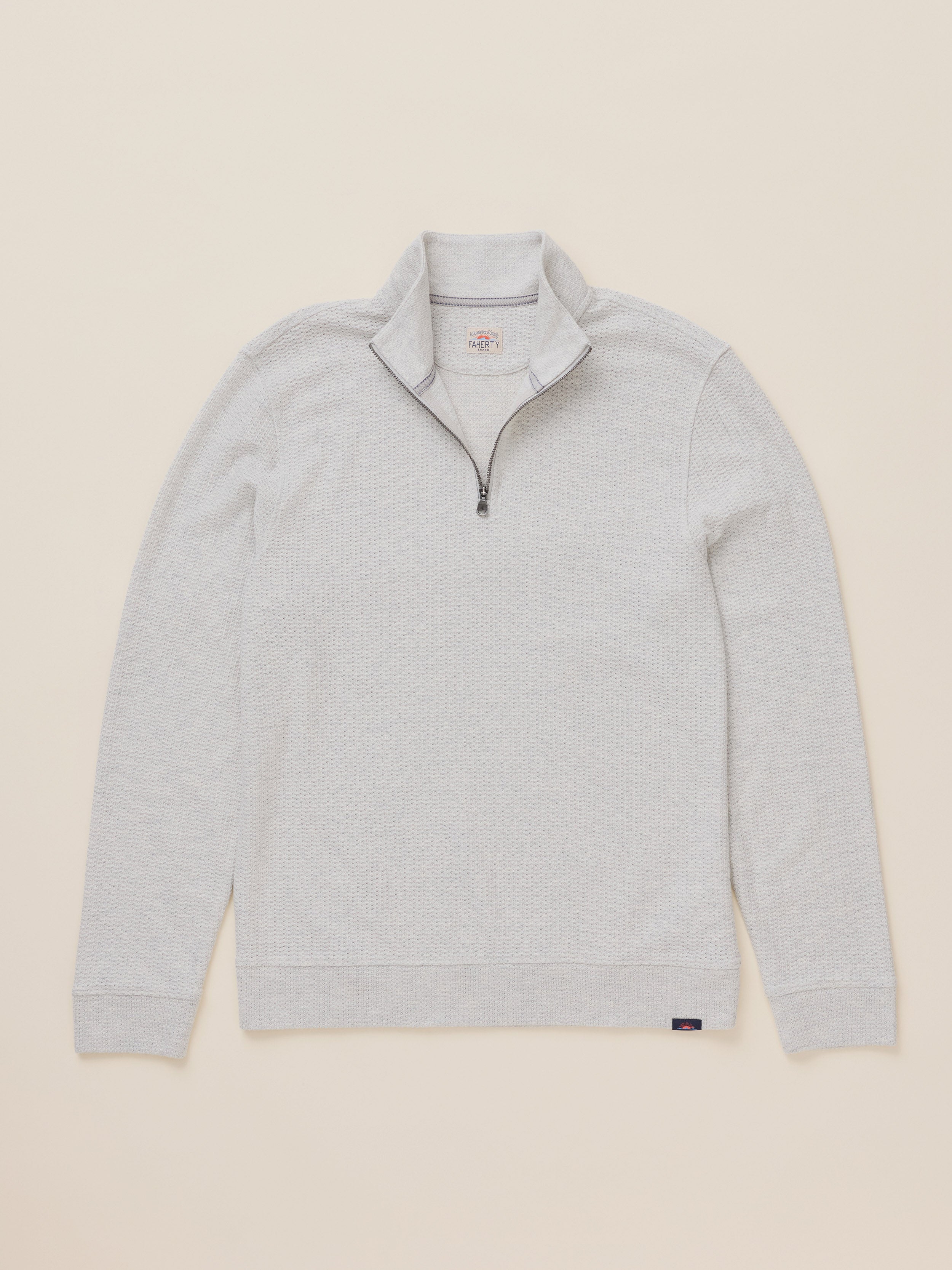 A light gray heather quarter-zip pullover sweater with a stand collar, laid flat against a solid beige background.