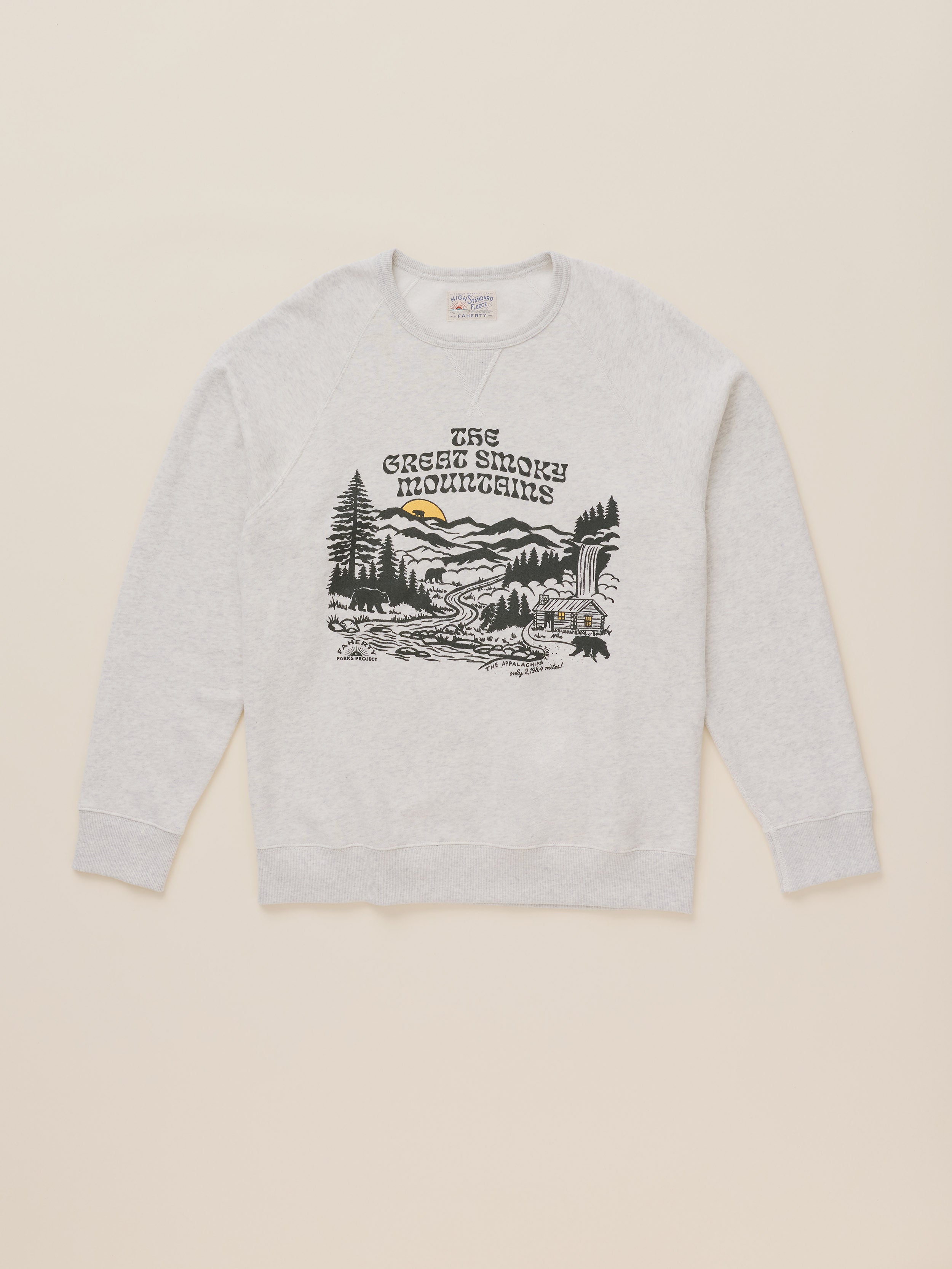 A light heather gray crewneck sweatshirt featuring a black and white graphic of 'The Green Smoke Mountains' with a small yellow sun detail, displayed flat against a light beige background.