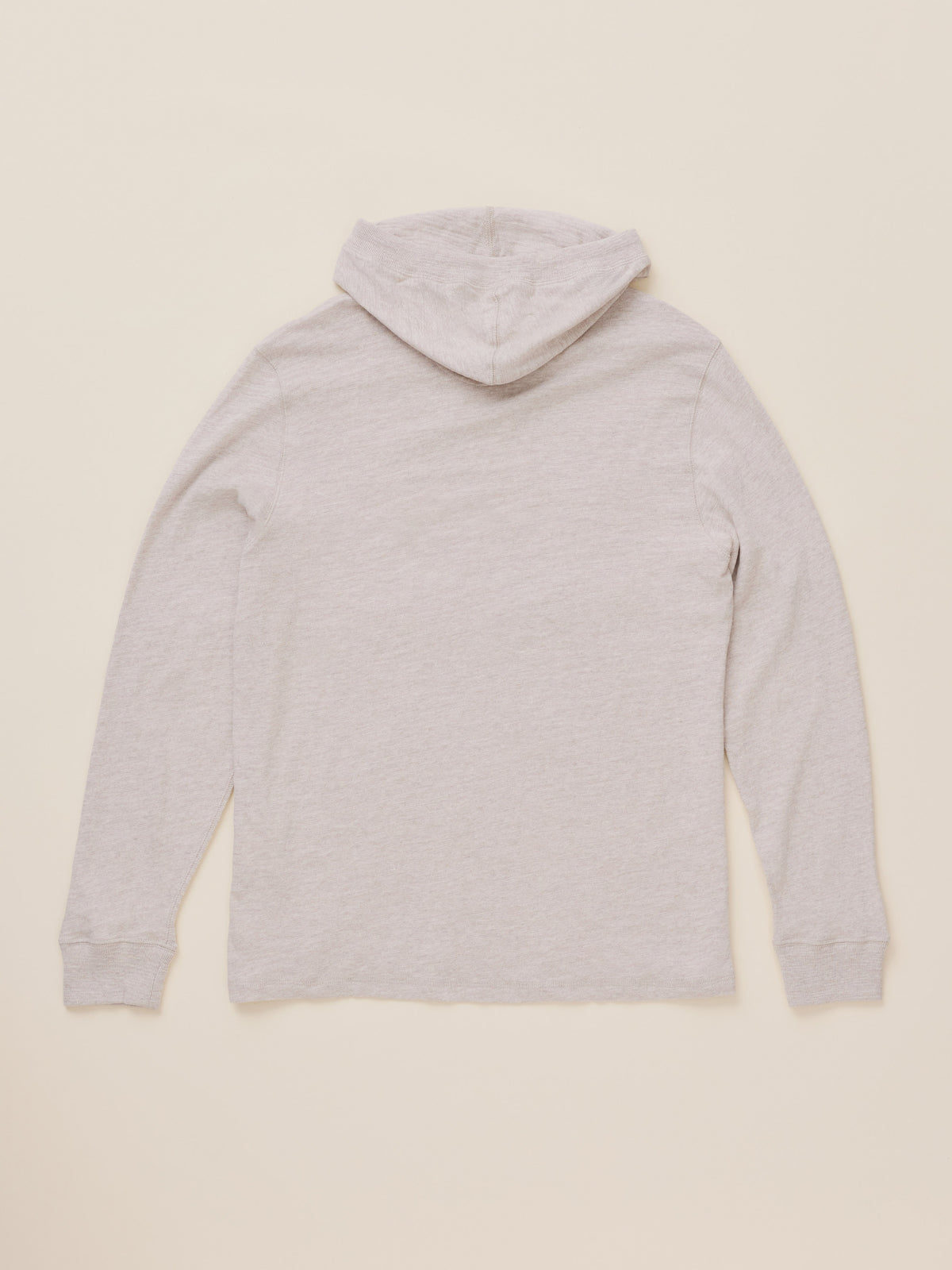An oatmeal heather hooded sweatshirt shown from the back, laid flat against a solid cream-colored background., image 7 of 7