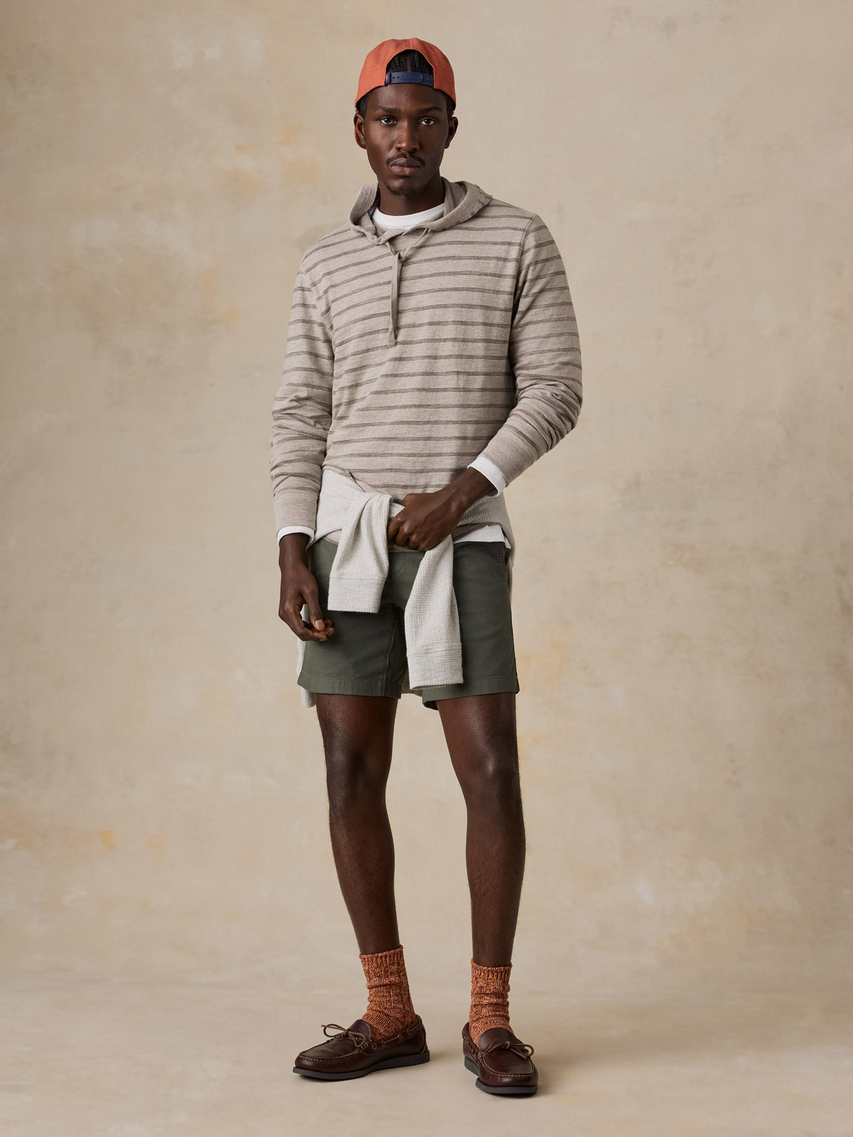 A man wearing a striped sweatshirt and green shorts, image 2 of 5