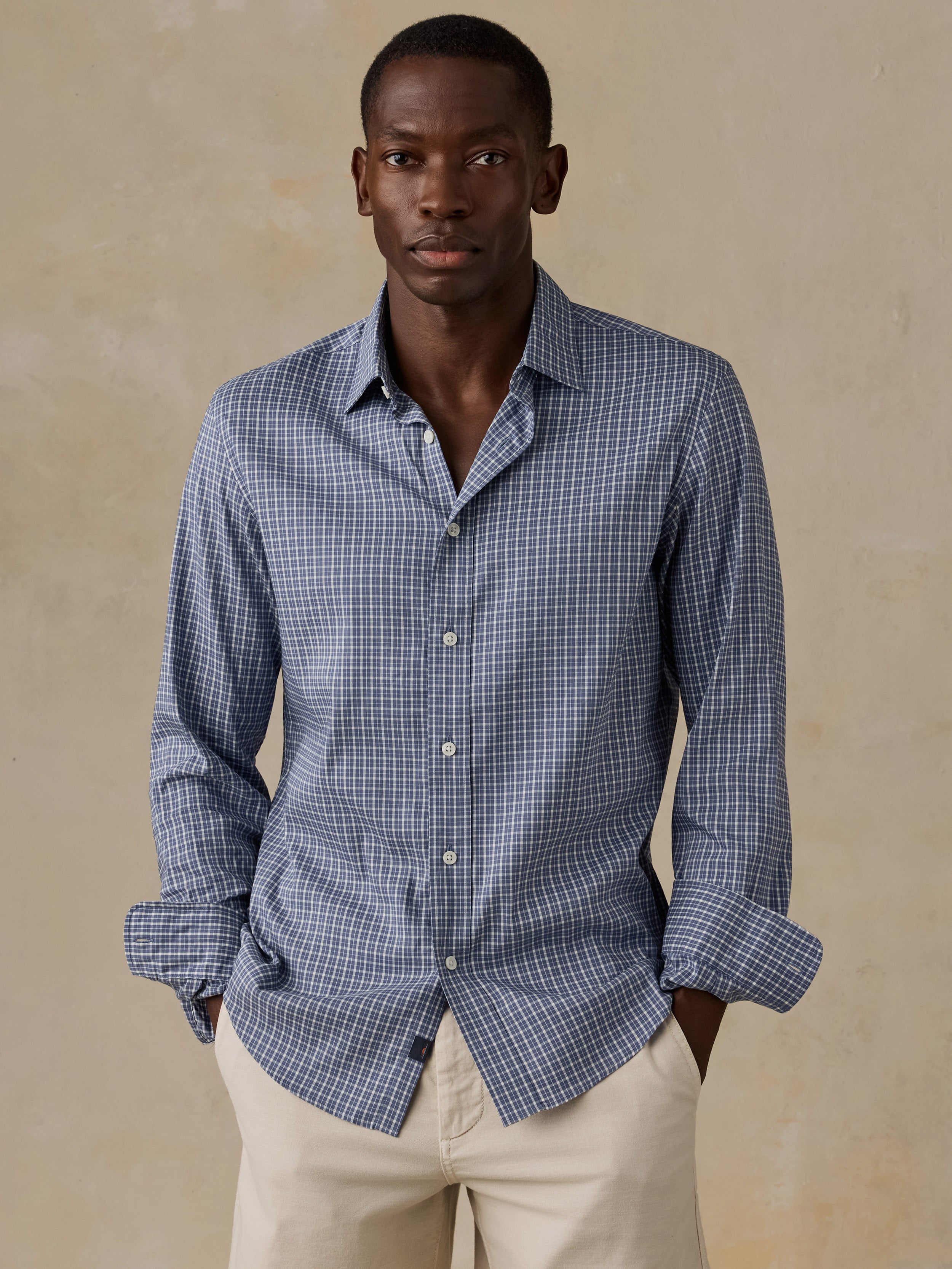 A man wearing a blue checkered shirt and beige shorts