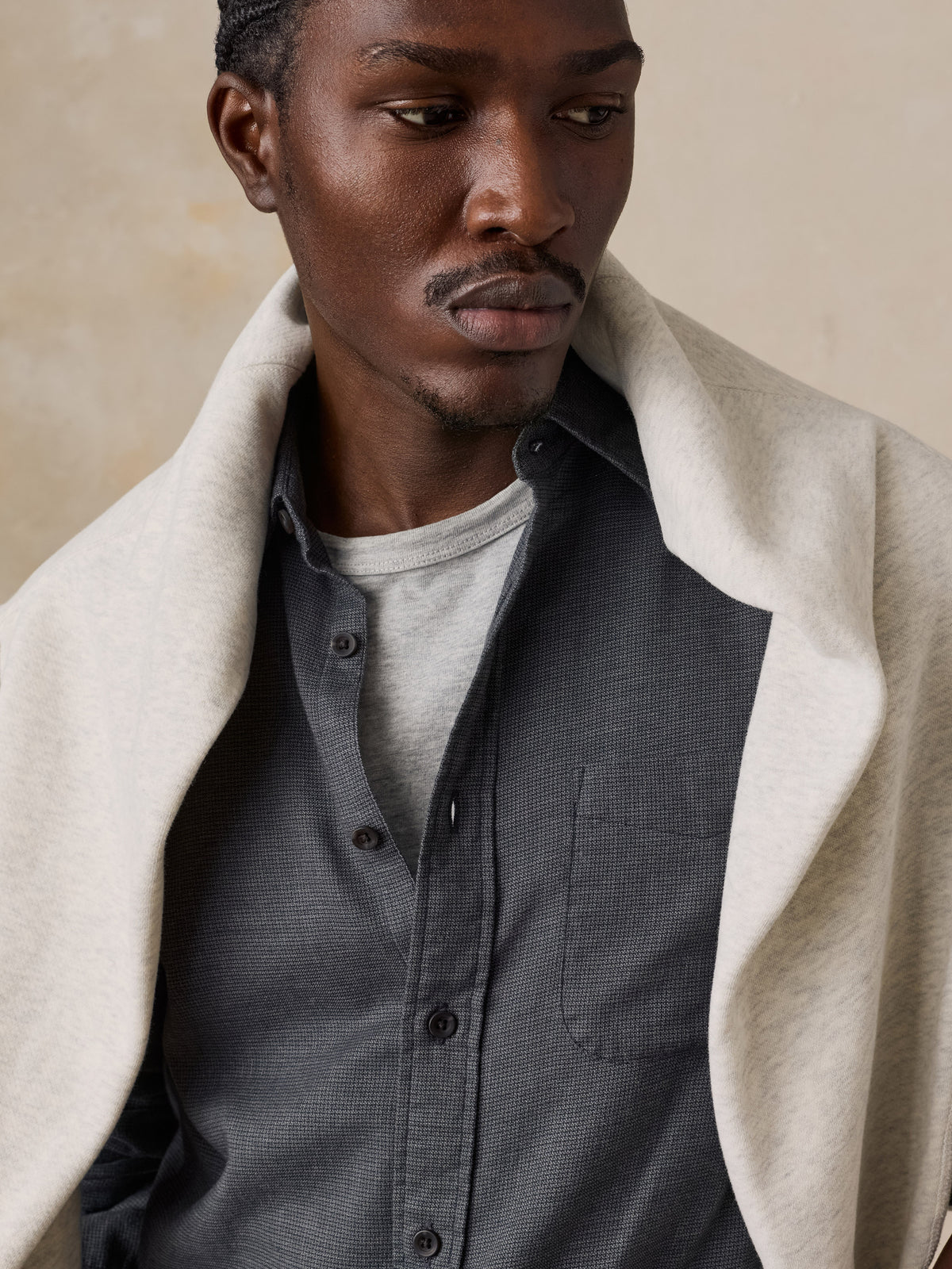 Close up of a man wearing a dark grey button down shirt and grey pants, image 3 of 5