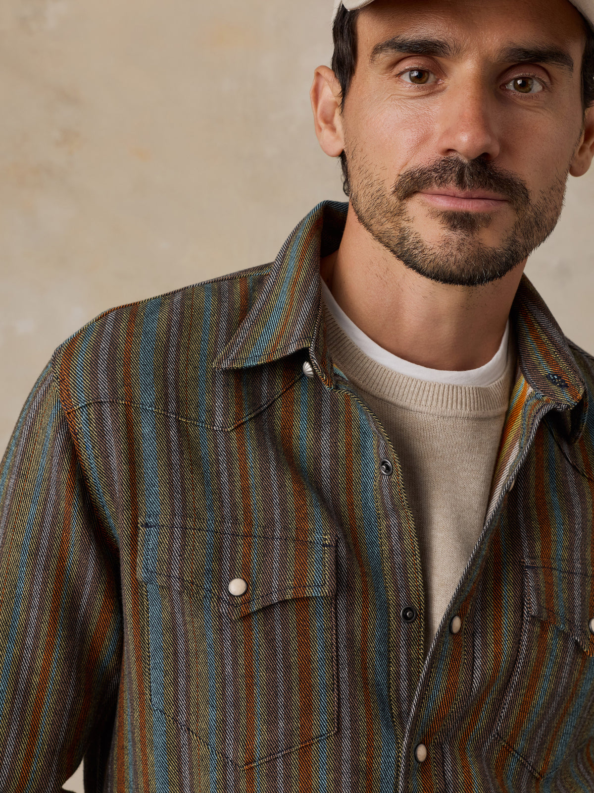 A man wearing a striped button-down shirt with blue, green, and brown vertical stripes