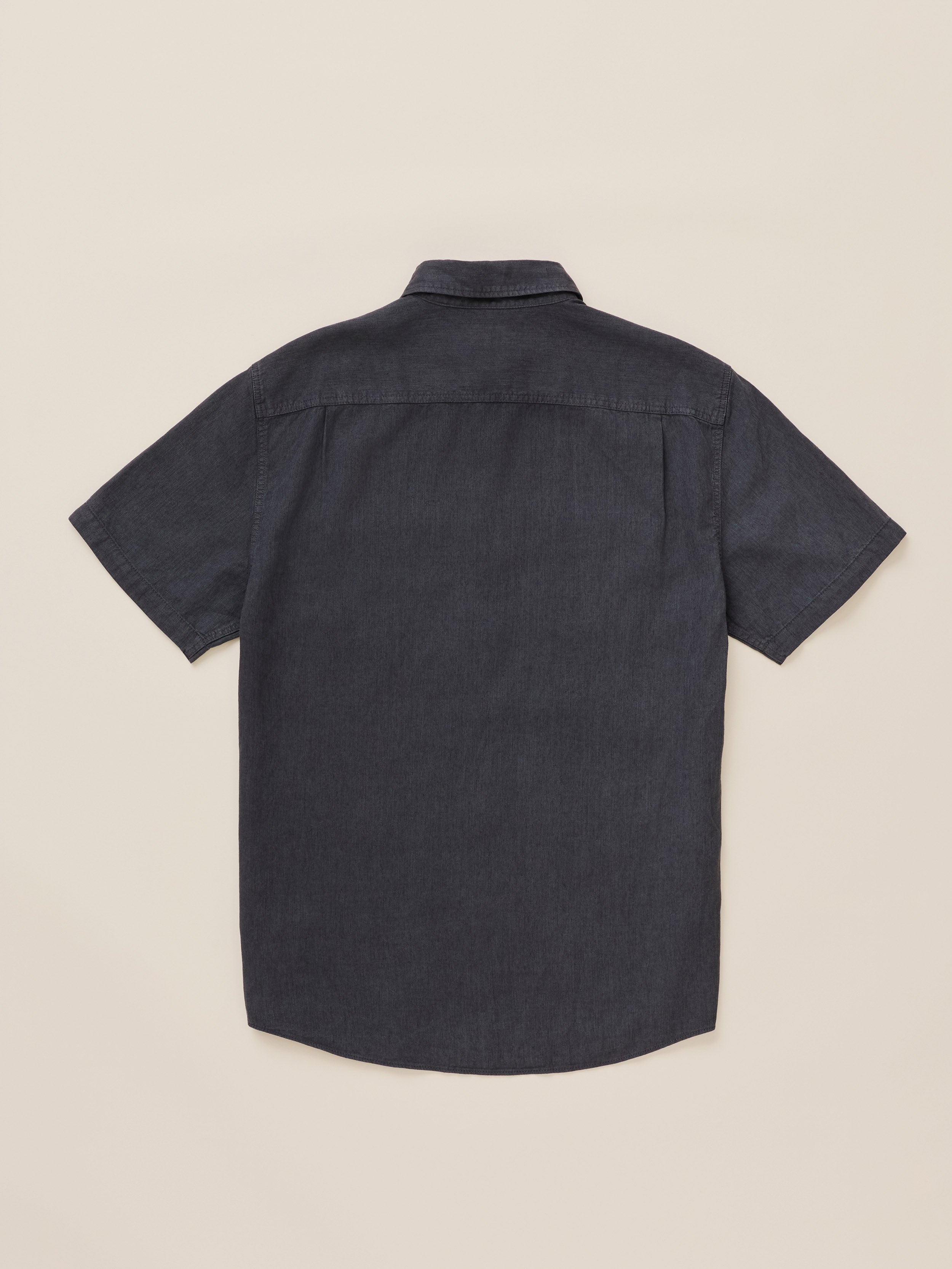 A dark charcoal gray short-sleeve button-down shirt shown from the back, laid flat against a light beige background.