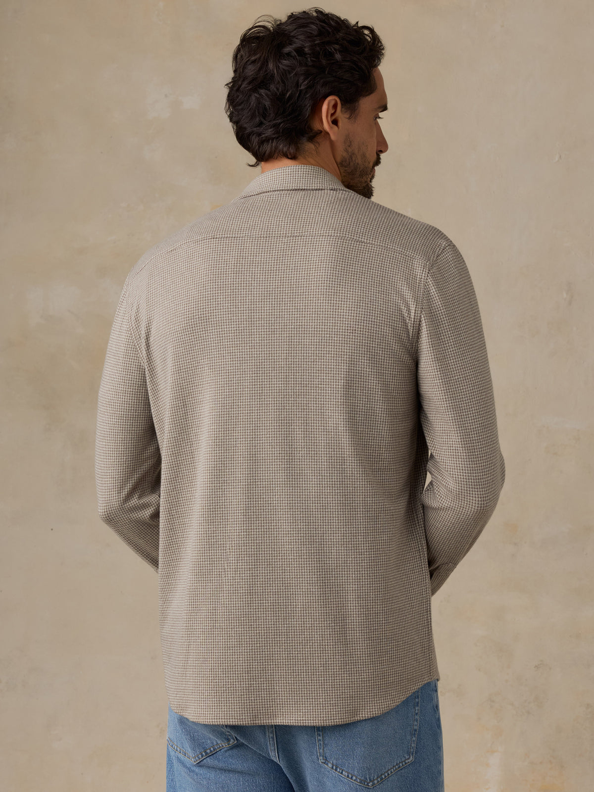 Man wearing a beige overshirt and jeans against a beige studio background, image 3 of 7