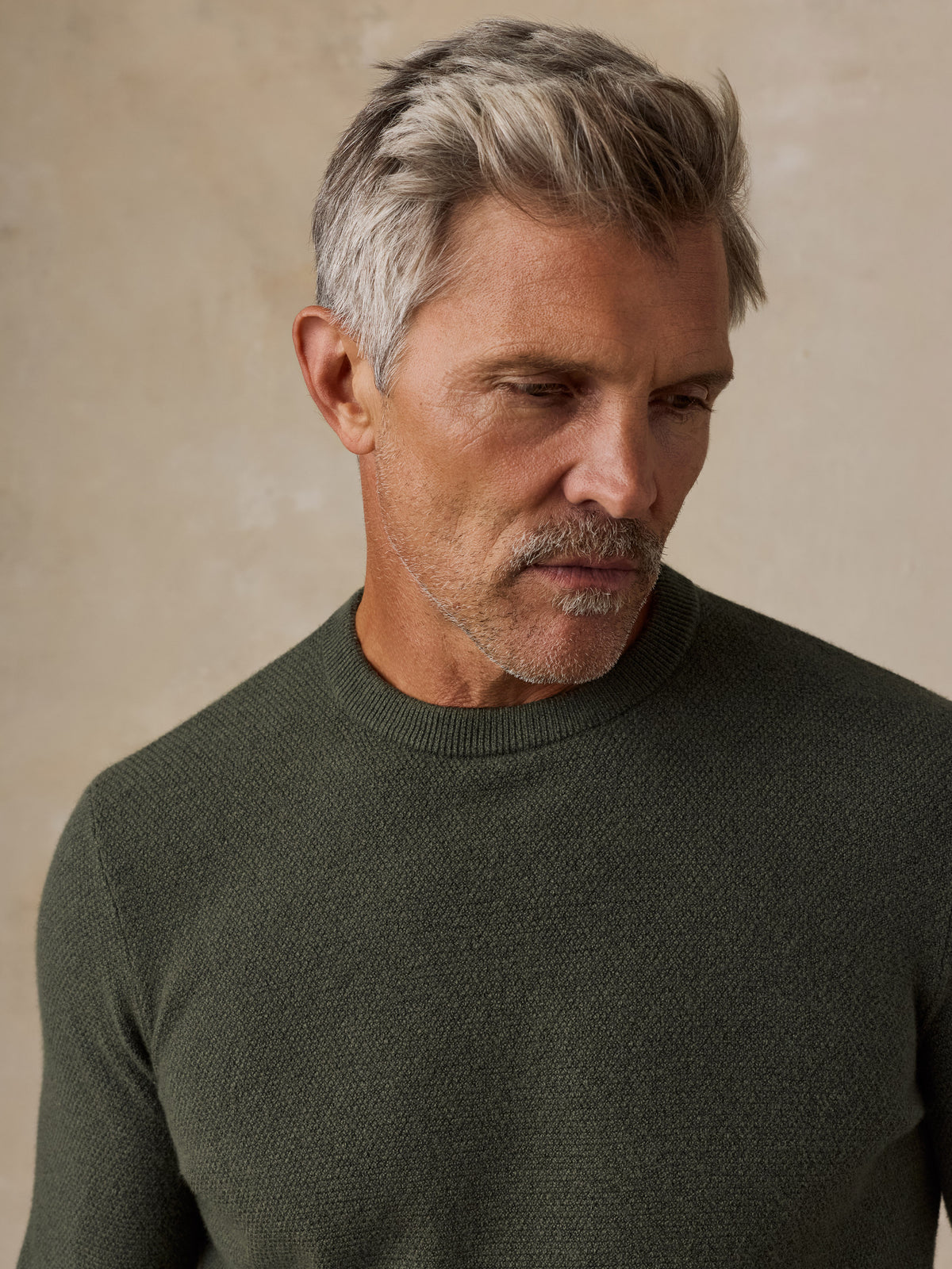 Close up of a man wearing a dark green sweater, image 4 of 5