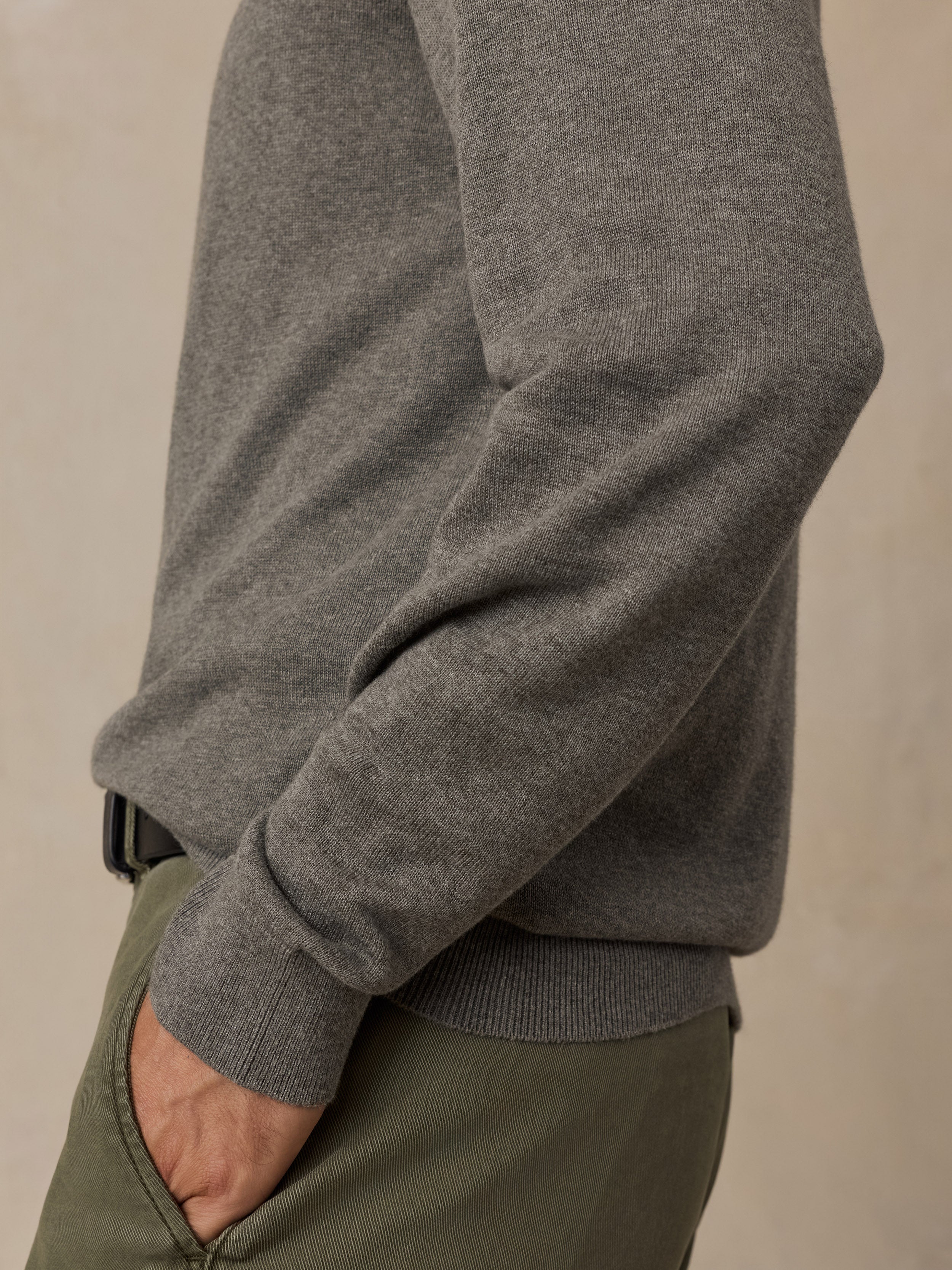 Close-up of a man wearing a green knit sweater and olive green trousers.