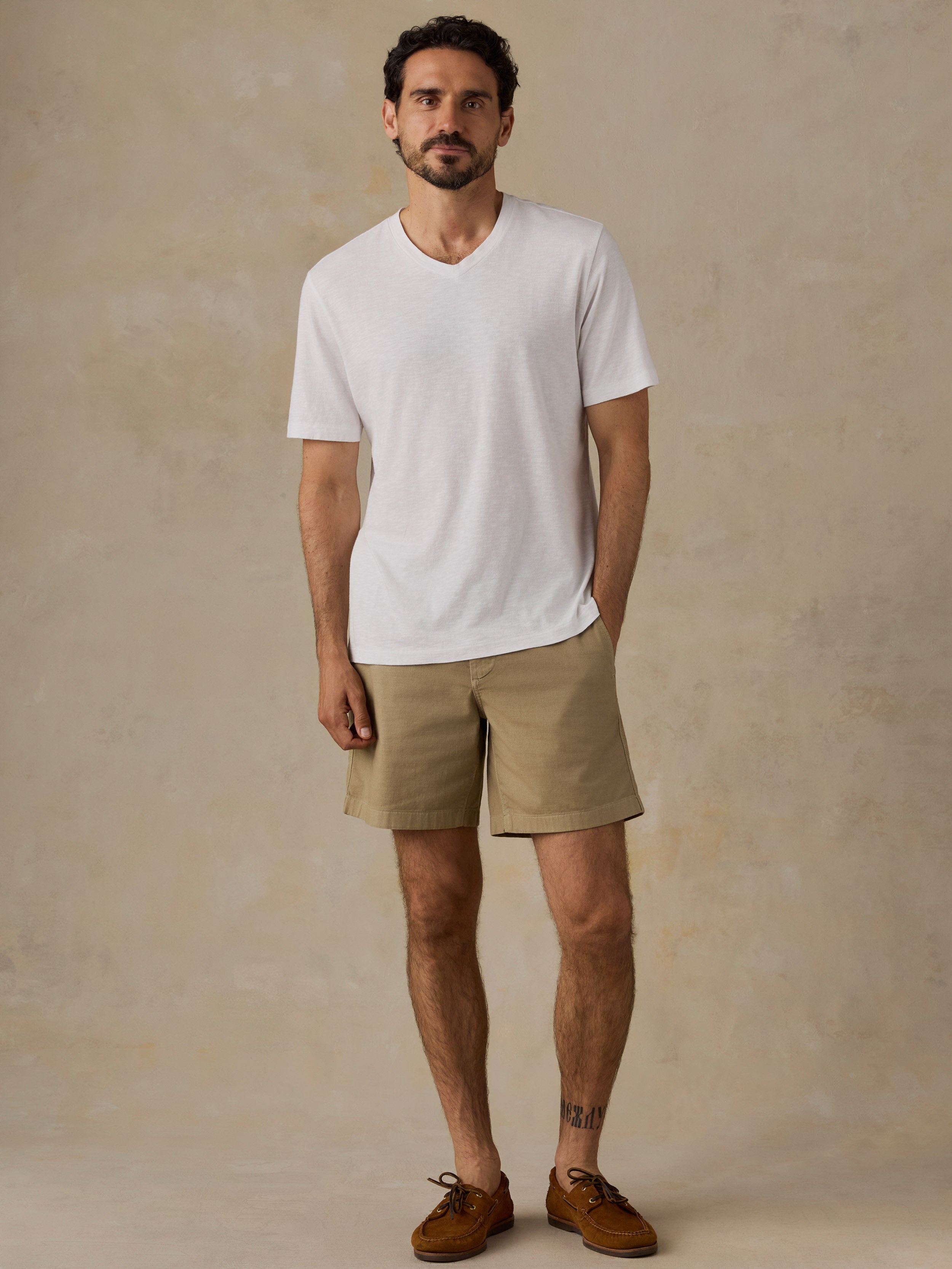 Man wearing a white t-shirt and blue jeans against a beige background