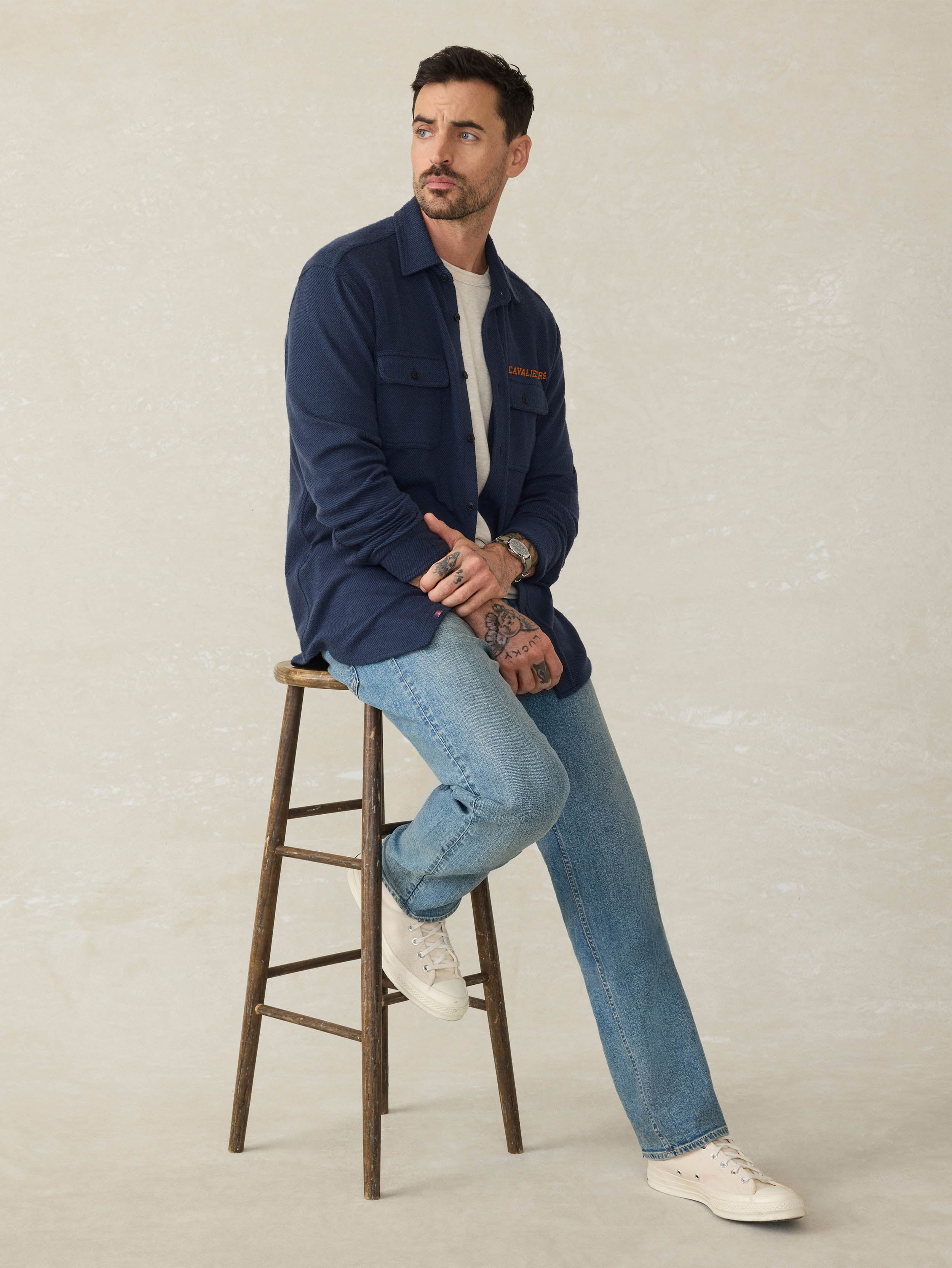 Man wearing a navy blue shirt with University of Virginia graphic against a beige background