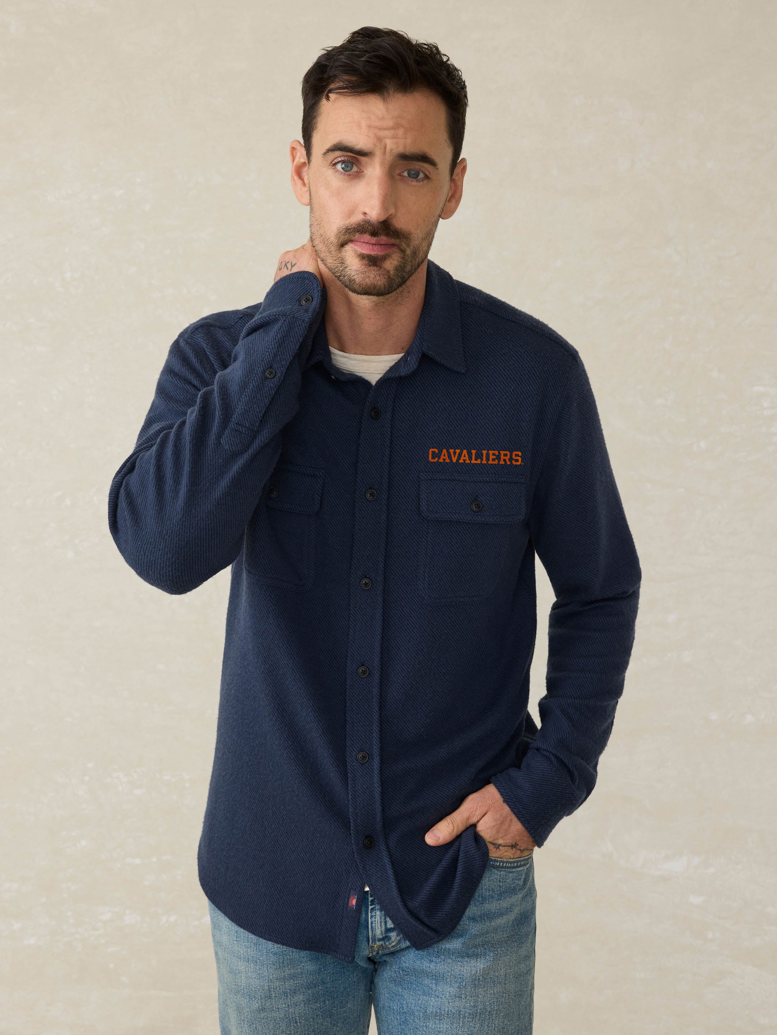 Man wearing a navy blue shirt with University of Virginia graphic against a beige background