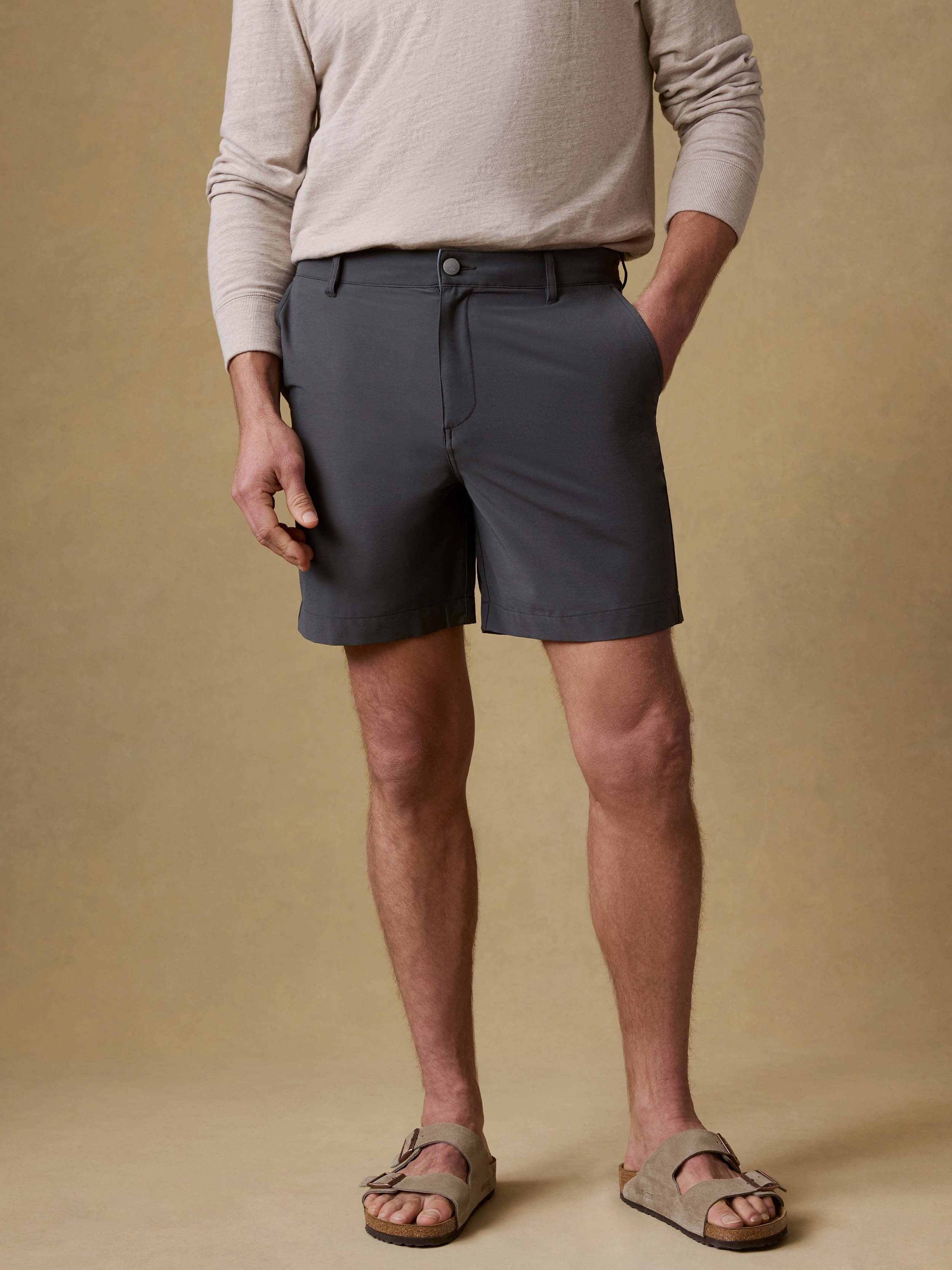 Man wearing grey shorts against a beige background