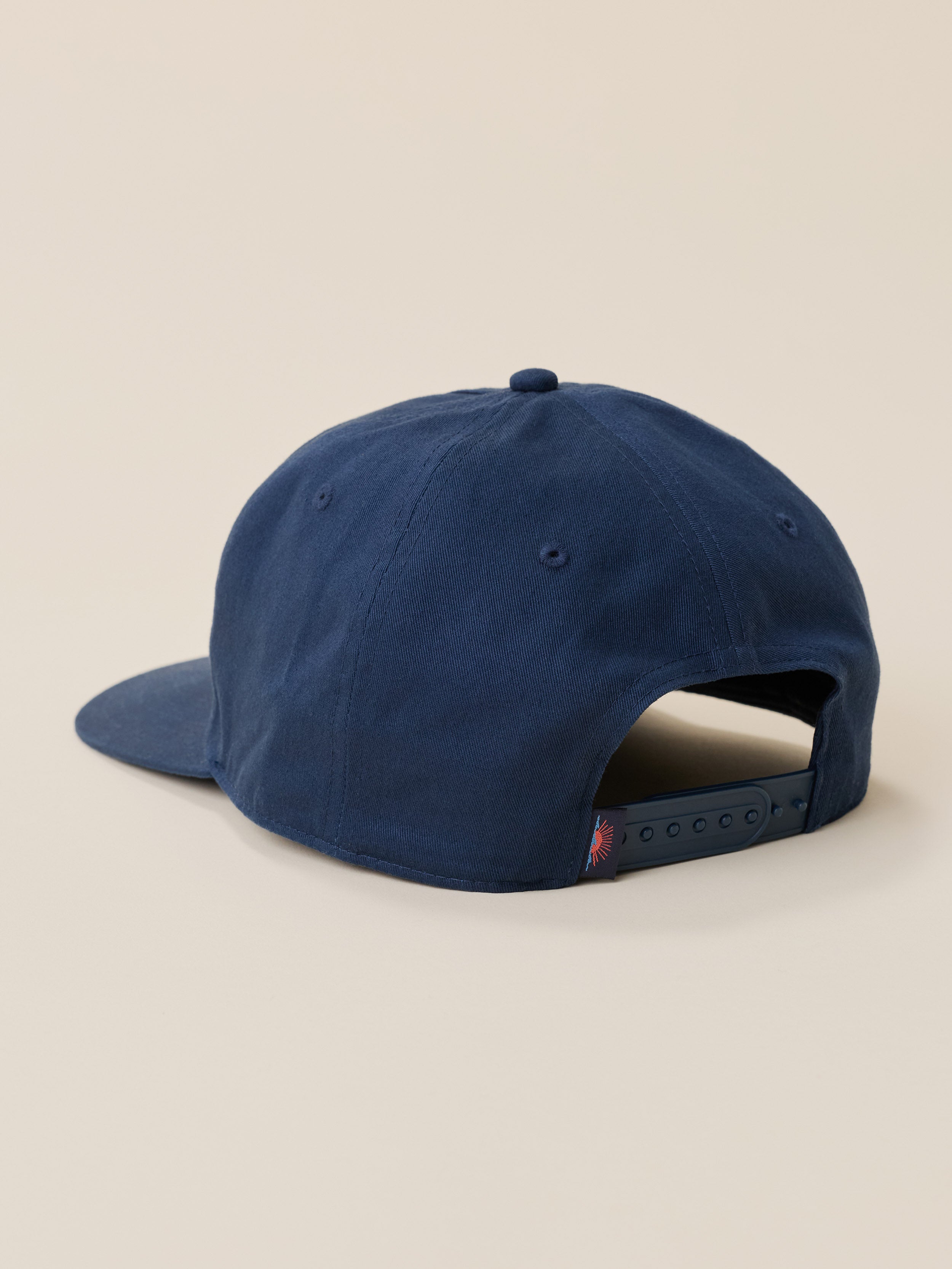 A navy blue baseball cap shown from a rear three-quarter angle on a solid beige background.