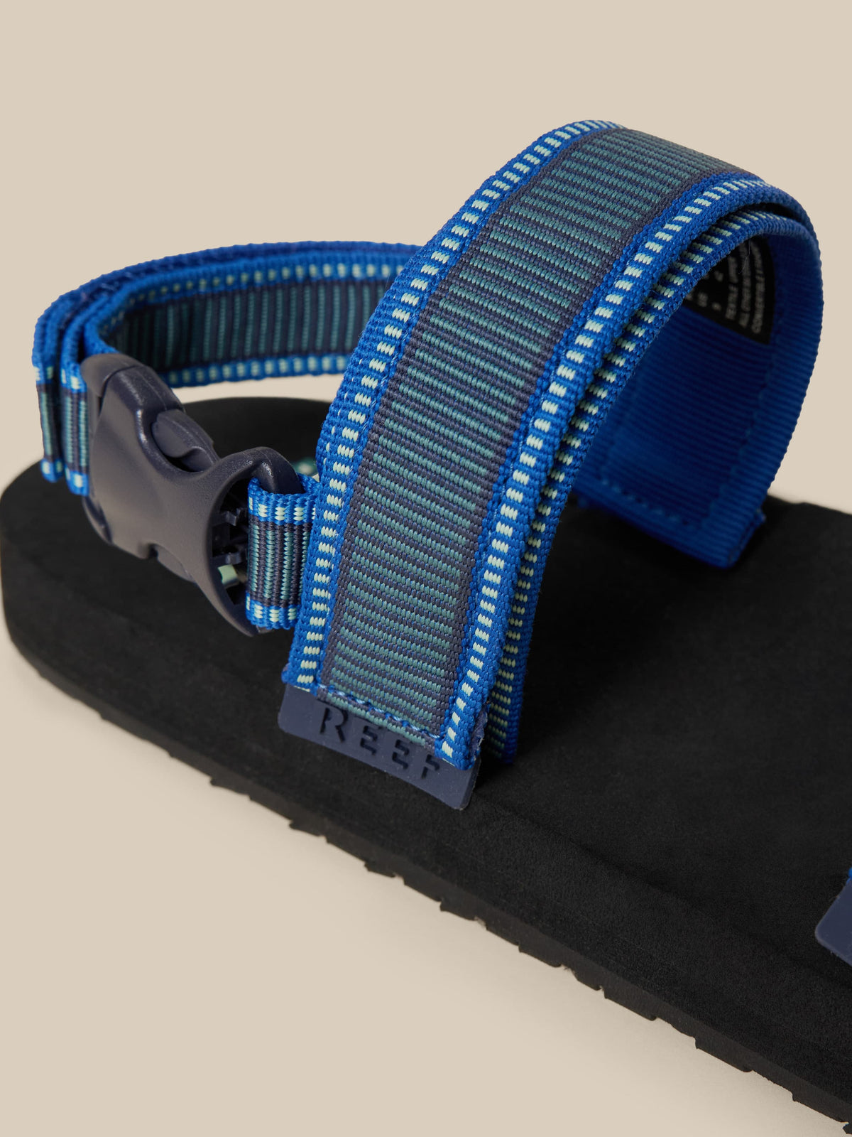 Blue and black sandal with a strap on a beige background, image 3 of 3