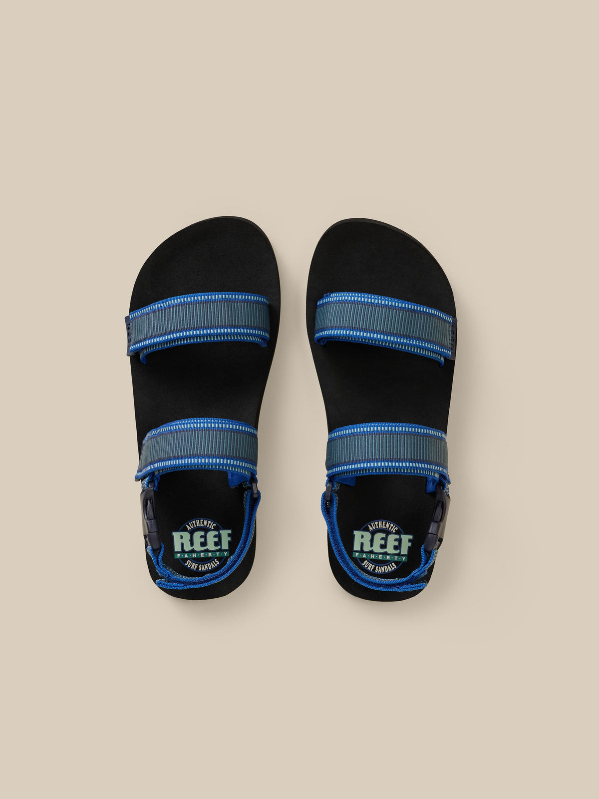 Black sandals with blue straps on a beige background, image 1 of 3
