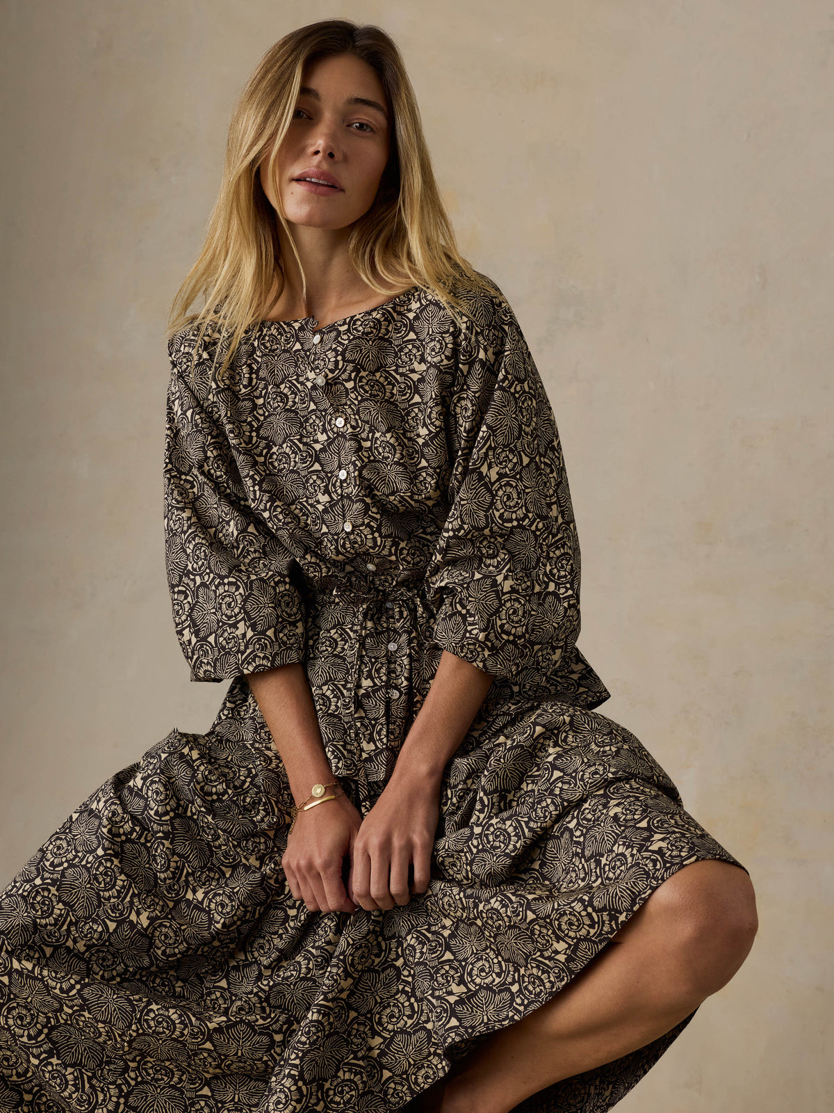 Woman wearing a floral patterned top and matching skirt against a beige background, image 4 of 6