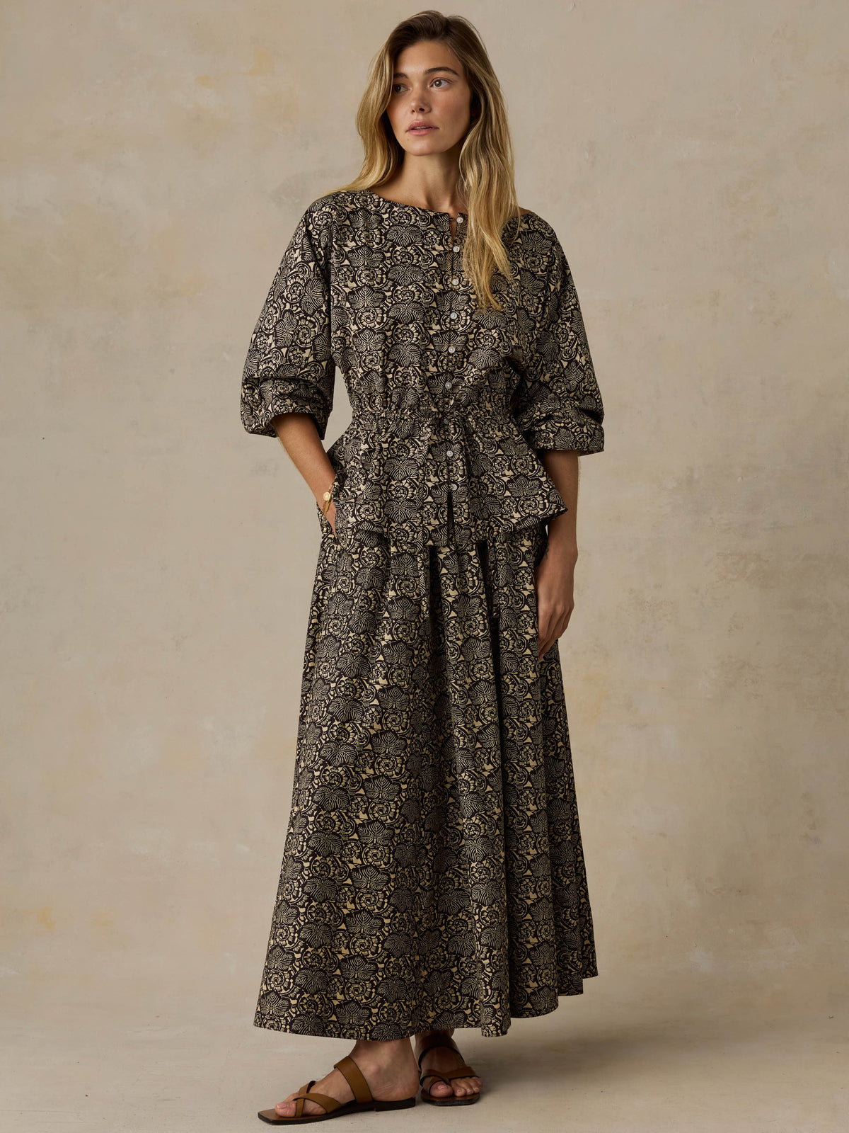 Woman wearing a floral patterned top and matching skirt against a beige background, image 2 of 6