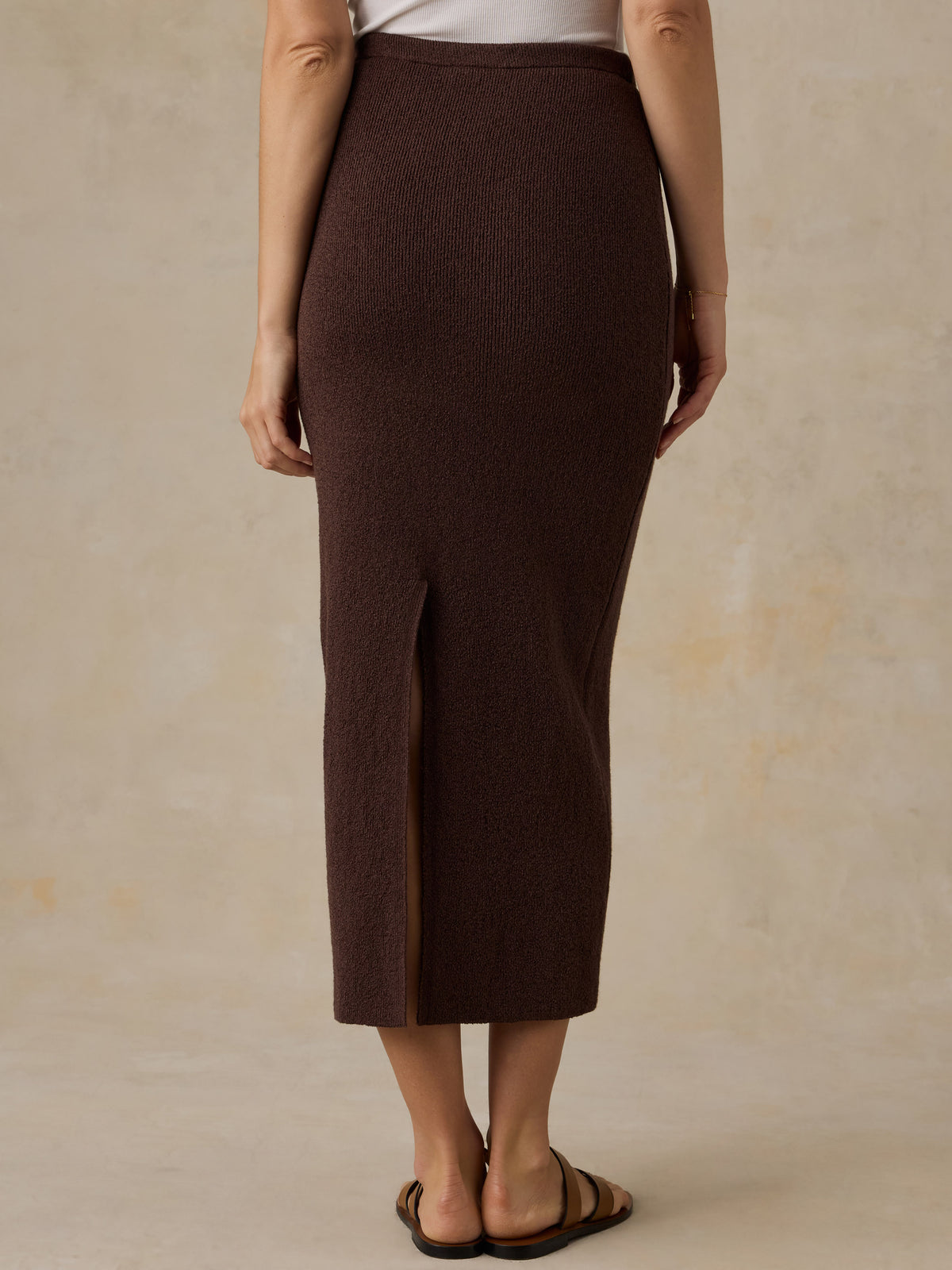Woman wearing a brown knit skirt and a white top against a beige background, image 4 of 5