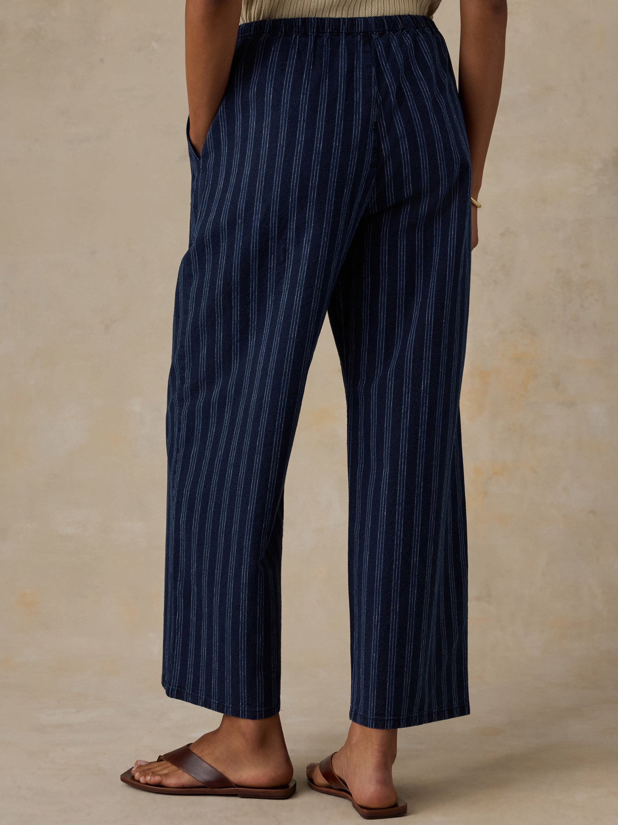 Woman wearing blue striped pants against a beige background