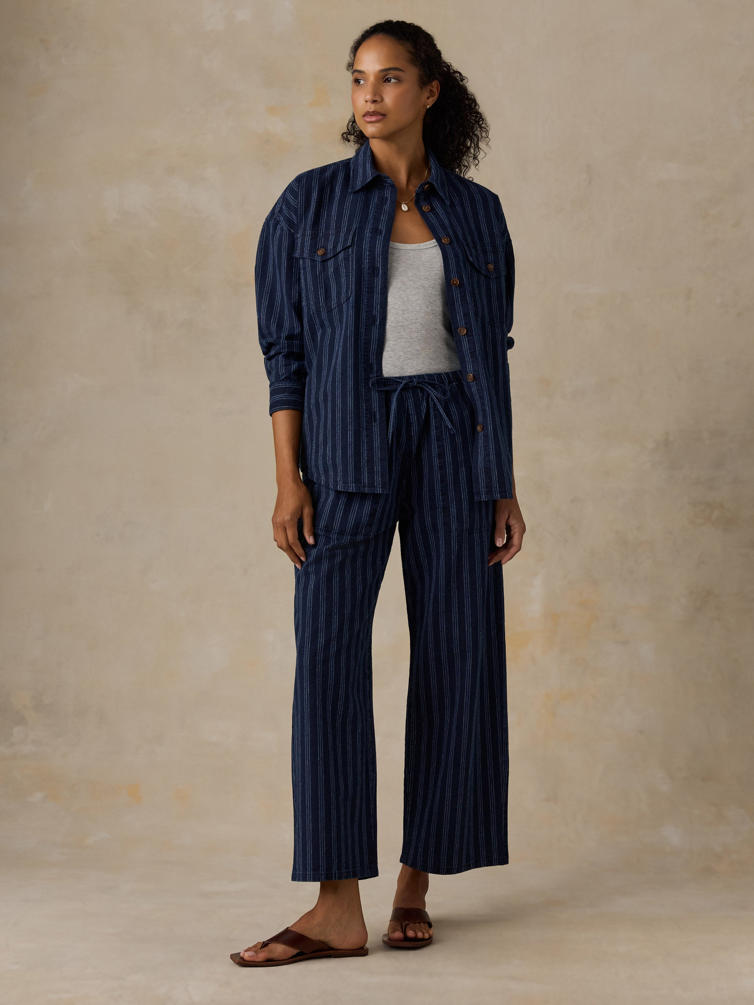 Woman wearing a blue striped top and matching pants against a beige background