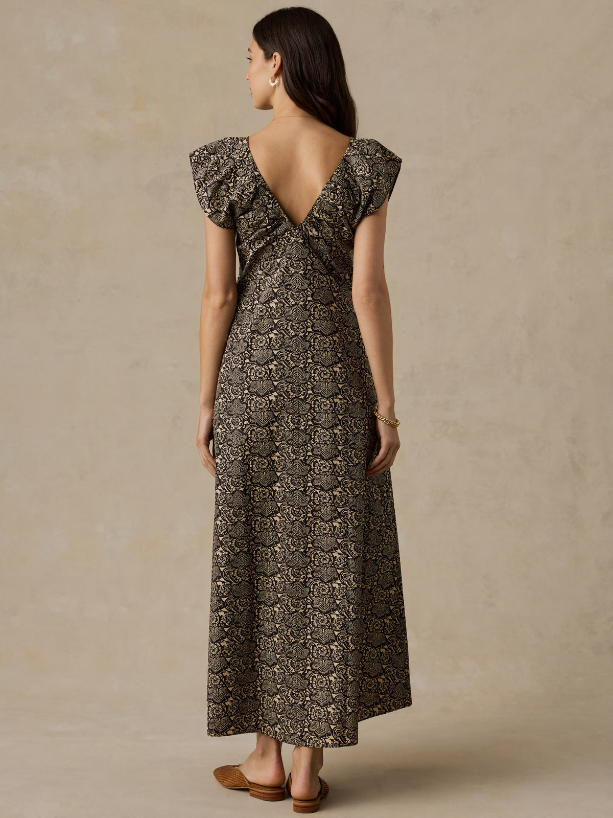 Woman wearing a black and beige floral printed dress against a beige background, image 5 of 6