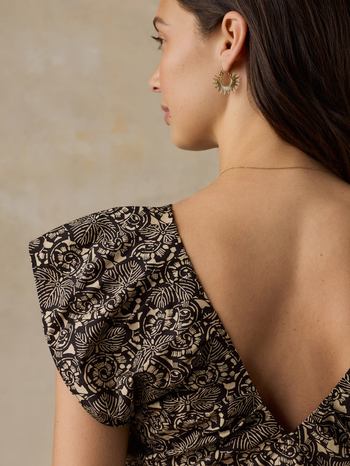 Woman wearing a black and beige floral printed dress against a beige background, image 6 of 6