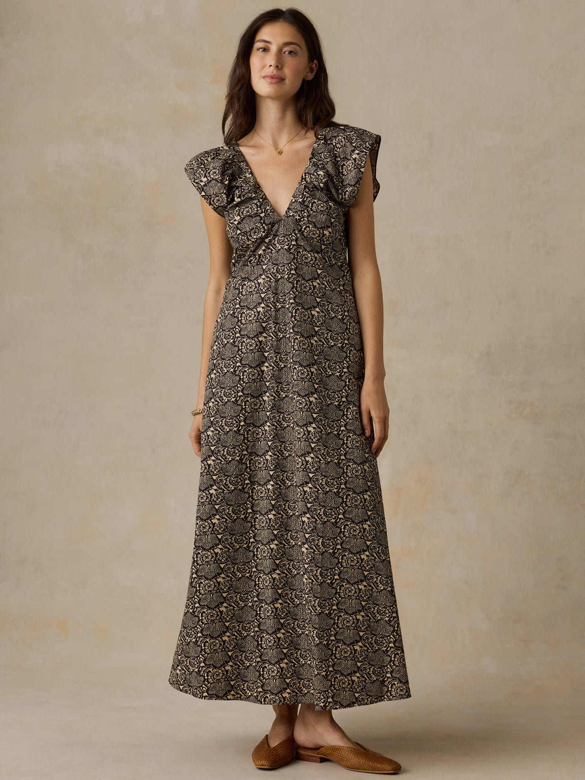 Woman wearing a black and beige floral printed dress against a beige background, image 1 of 6