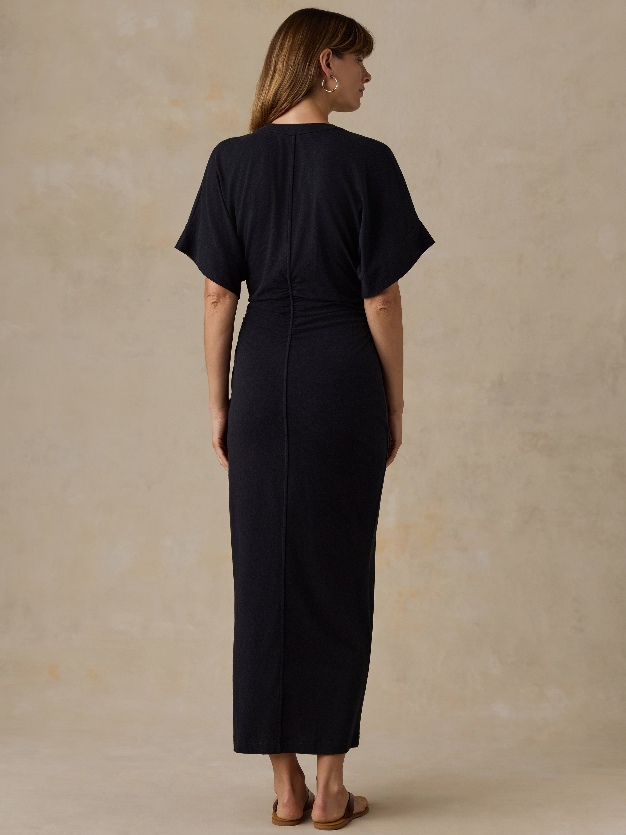 Woman wearing a black maxi dress against a beige background
