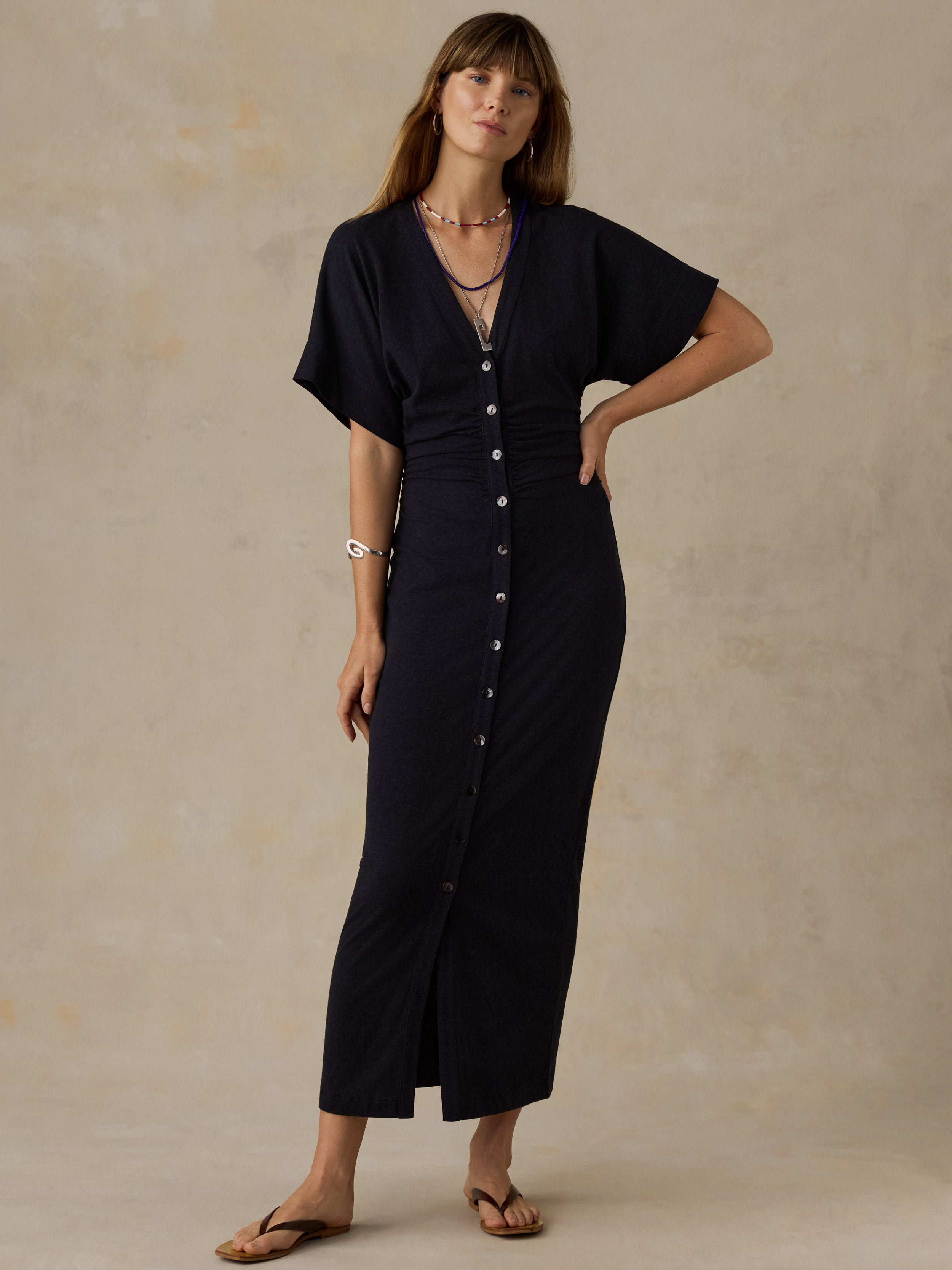 Woman wearing a black maxi dress against a beige background