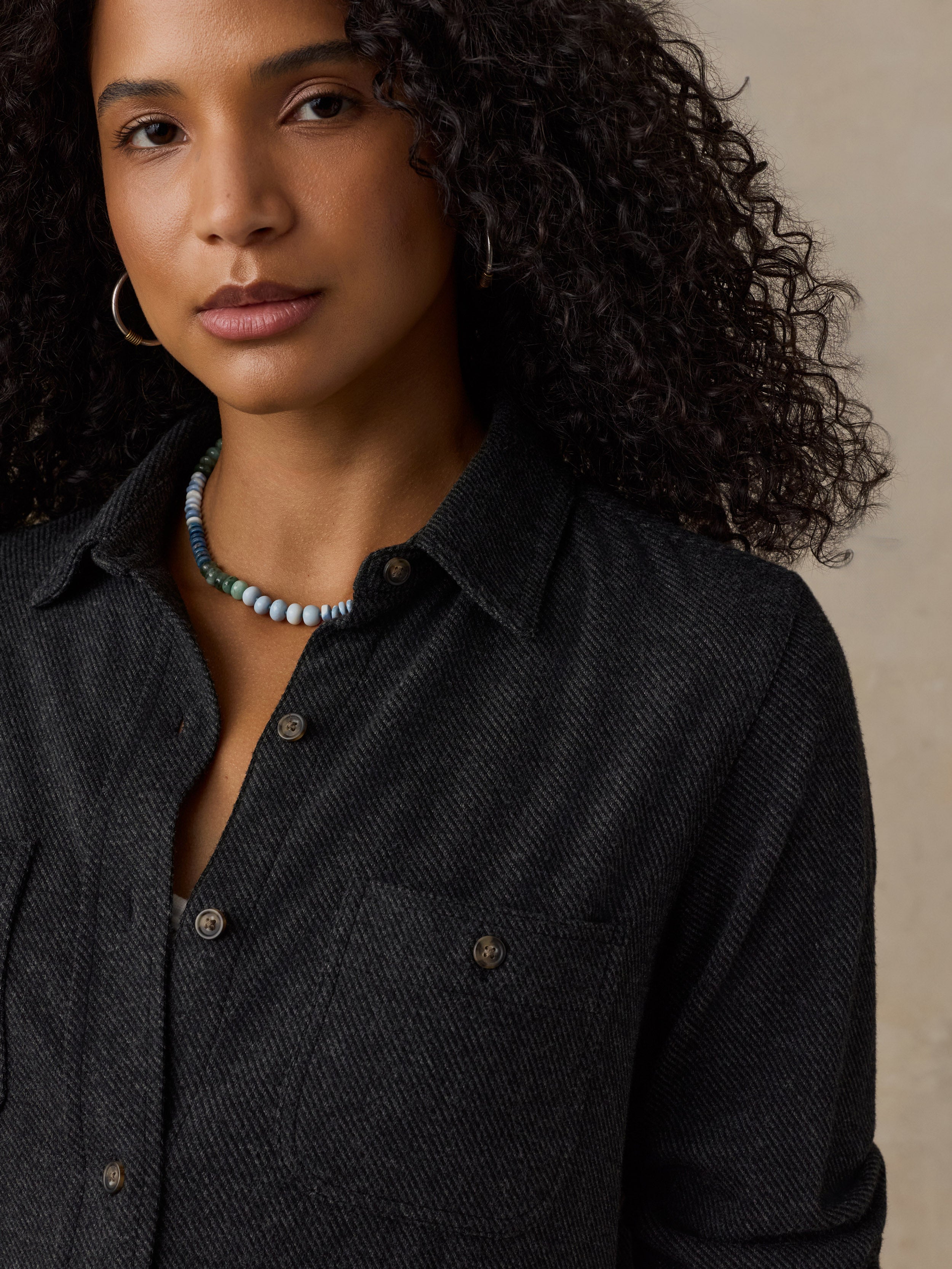 Woman wearing a black sweater shirt against a beige background