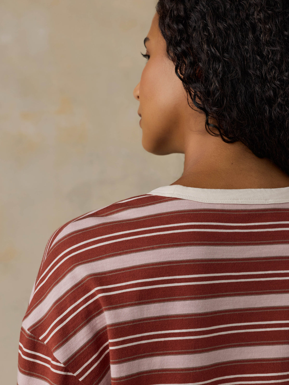 Woman wearing a red and pink striped long-sleeve shirt against a beige background, image 7 of 7