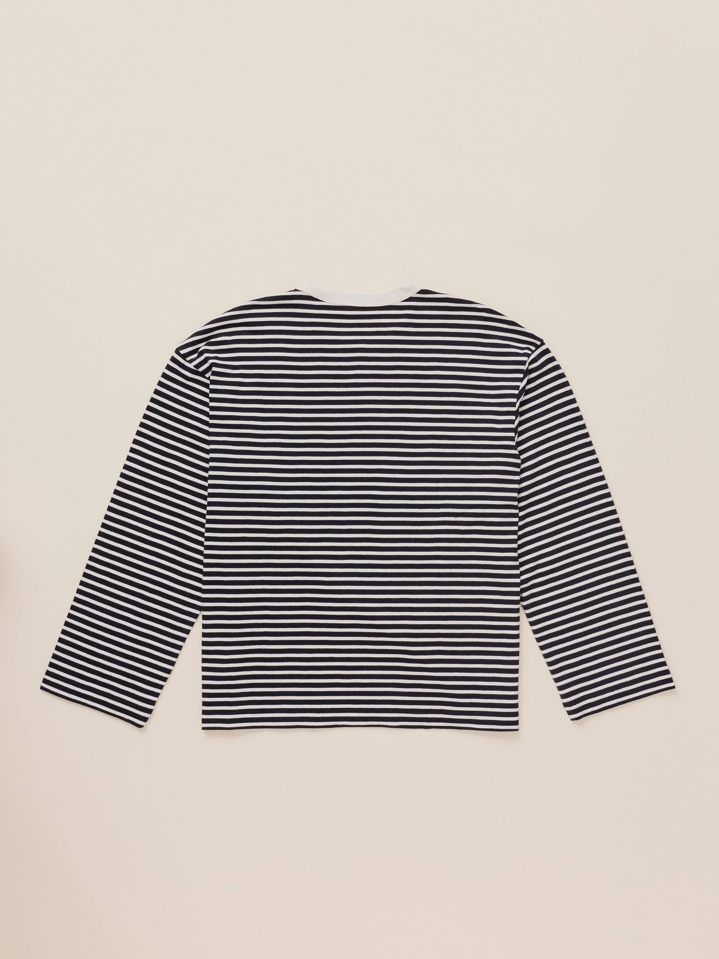 A long-sleeve striped top with horizontal black and white stripes, laid flat against a light beige background.