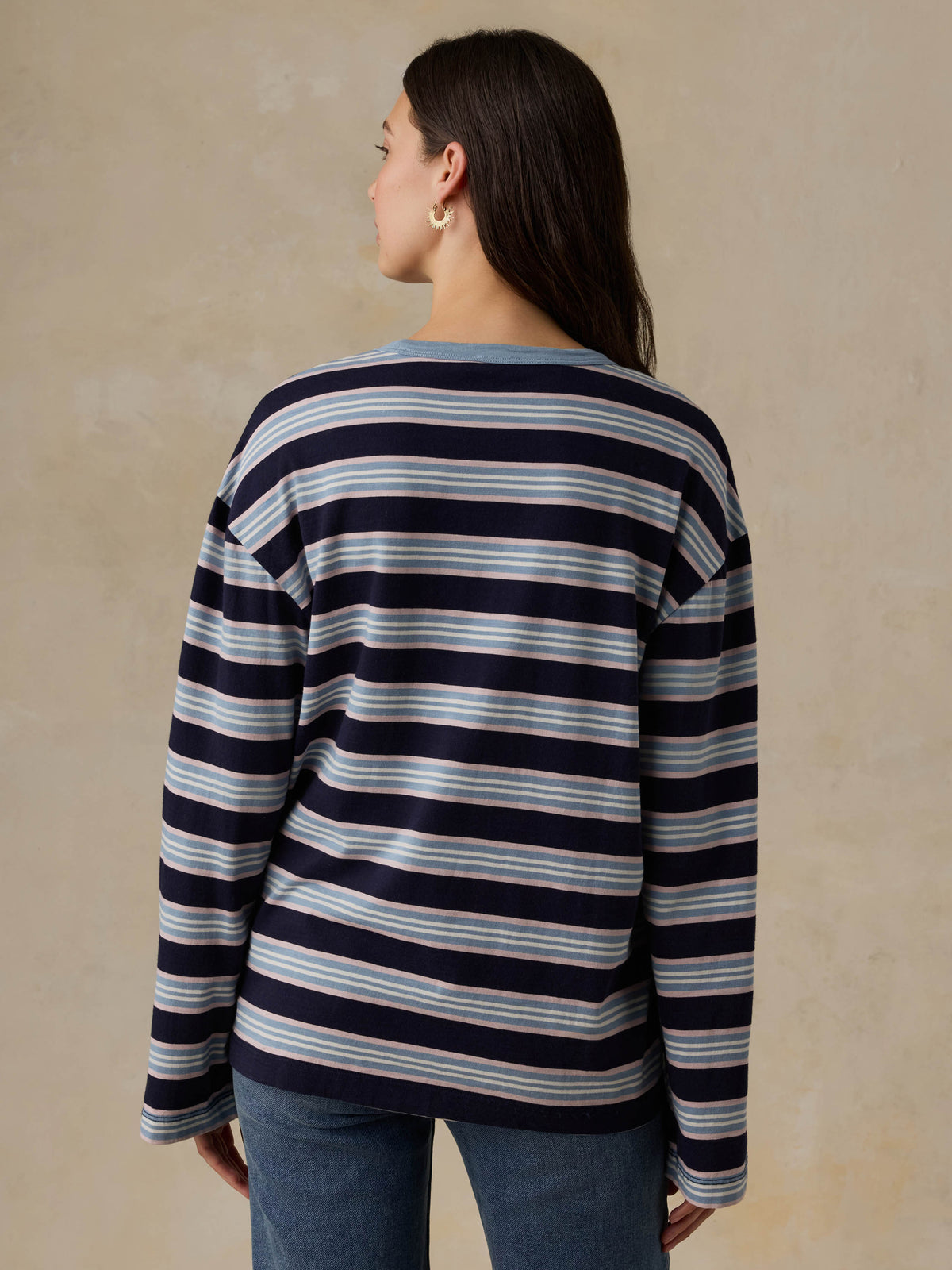 Woman wearing a blue striped shirt and jeans against a beige background, image 4 of 8
