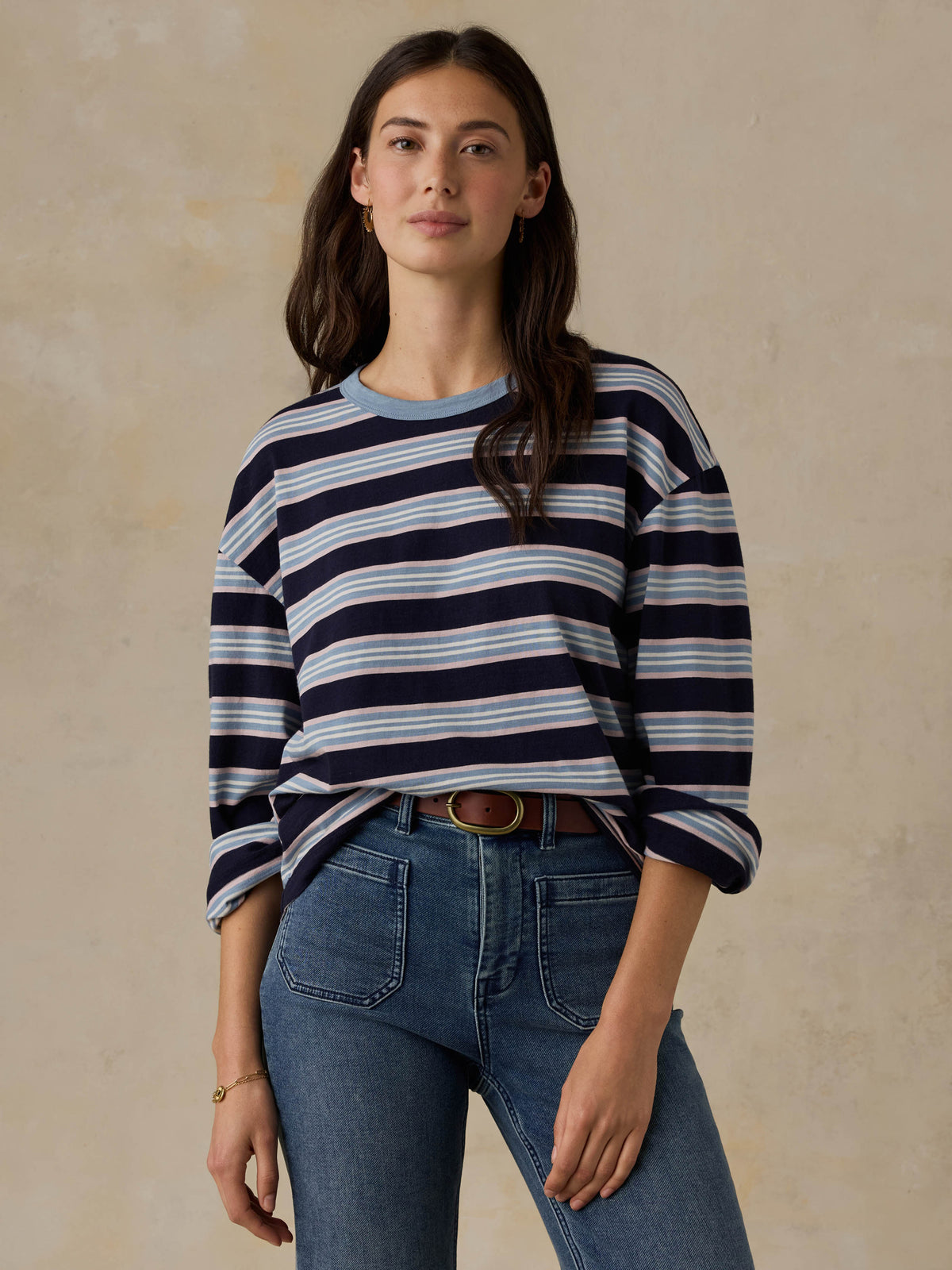 Woman wearing a blue striped shirt and jeans against a beige background, image 3 of 8