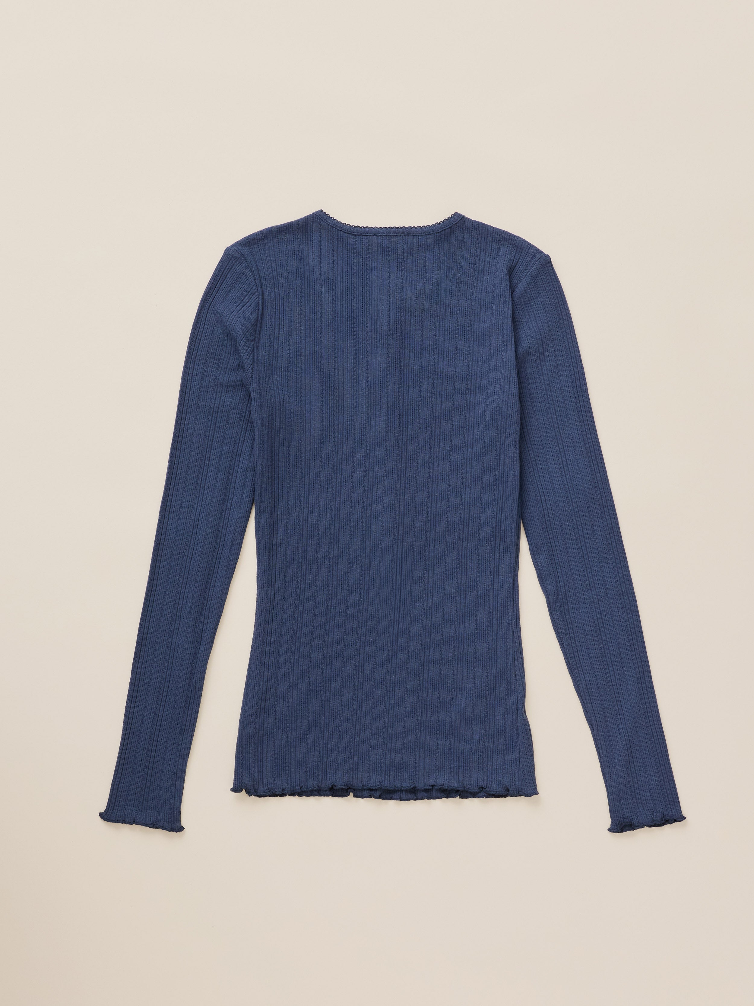 A dark blue ribbed long-sleeve top with a raw, frayed hem, laid flat against a light beige background.