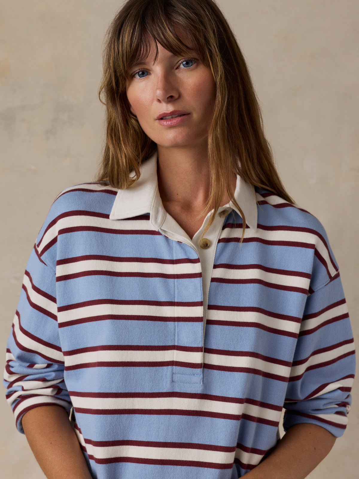 A woman wearing a light blue, white, and burgundy striped long-sleeve rugby shirt, image 3 of 7