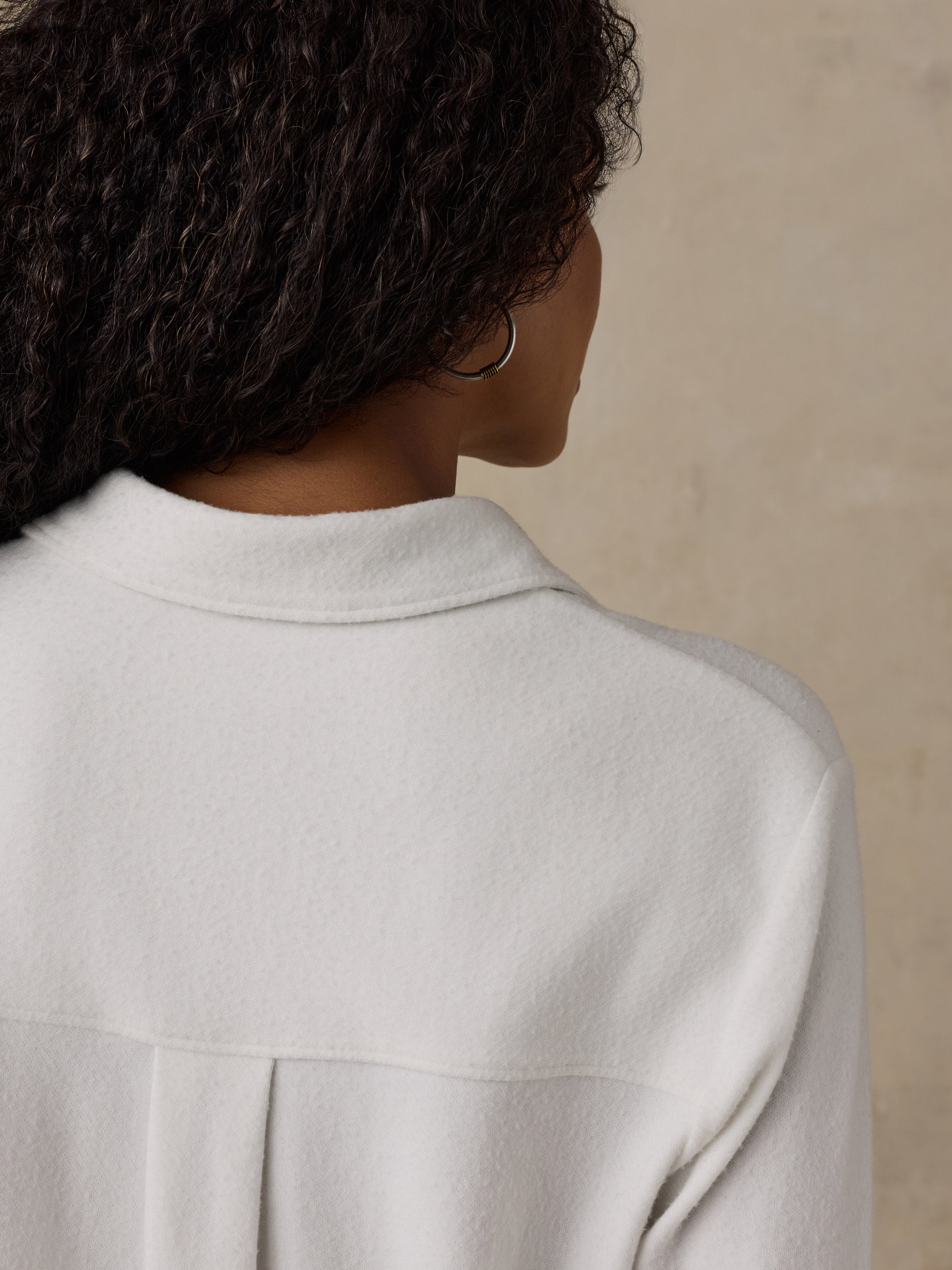 Woman wearing a white button up shirt against a beige background