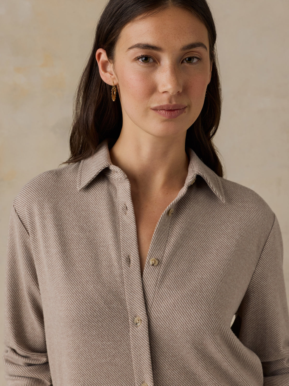 Woman wearing a beige button down shirt against a beige background, image 5 of 6