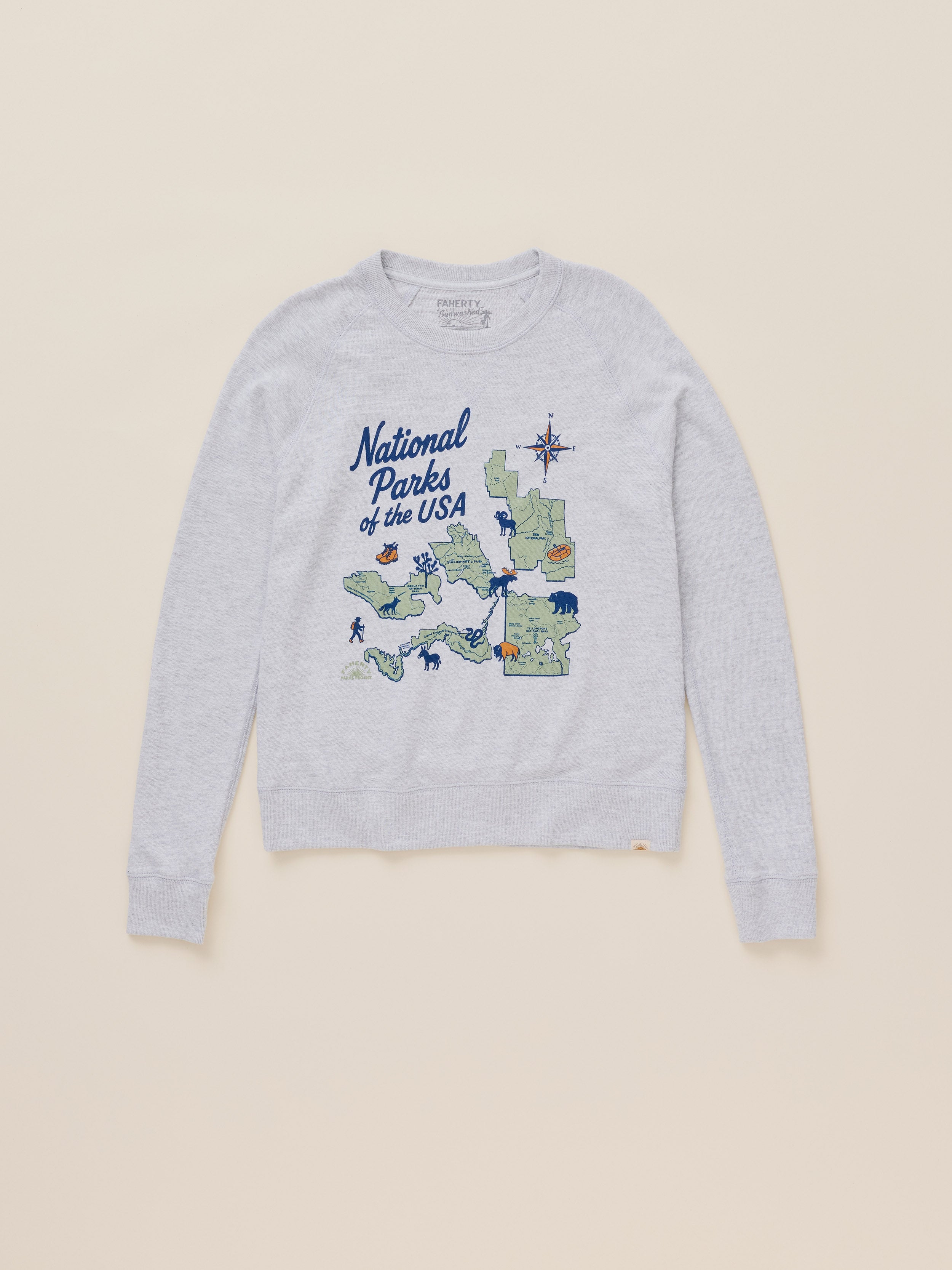A light heather gray crewneck sweatshirt featuring a graphic print of a map of the National Parks of the USA with blue text, displayed flat against a solid beige background.