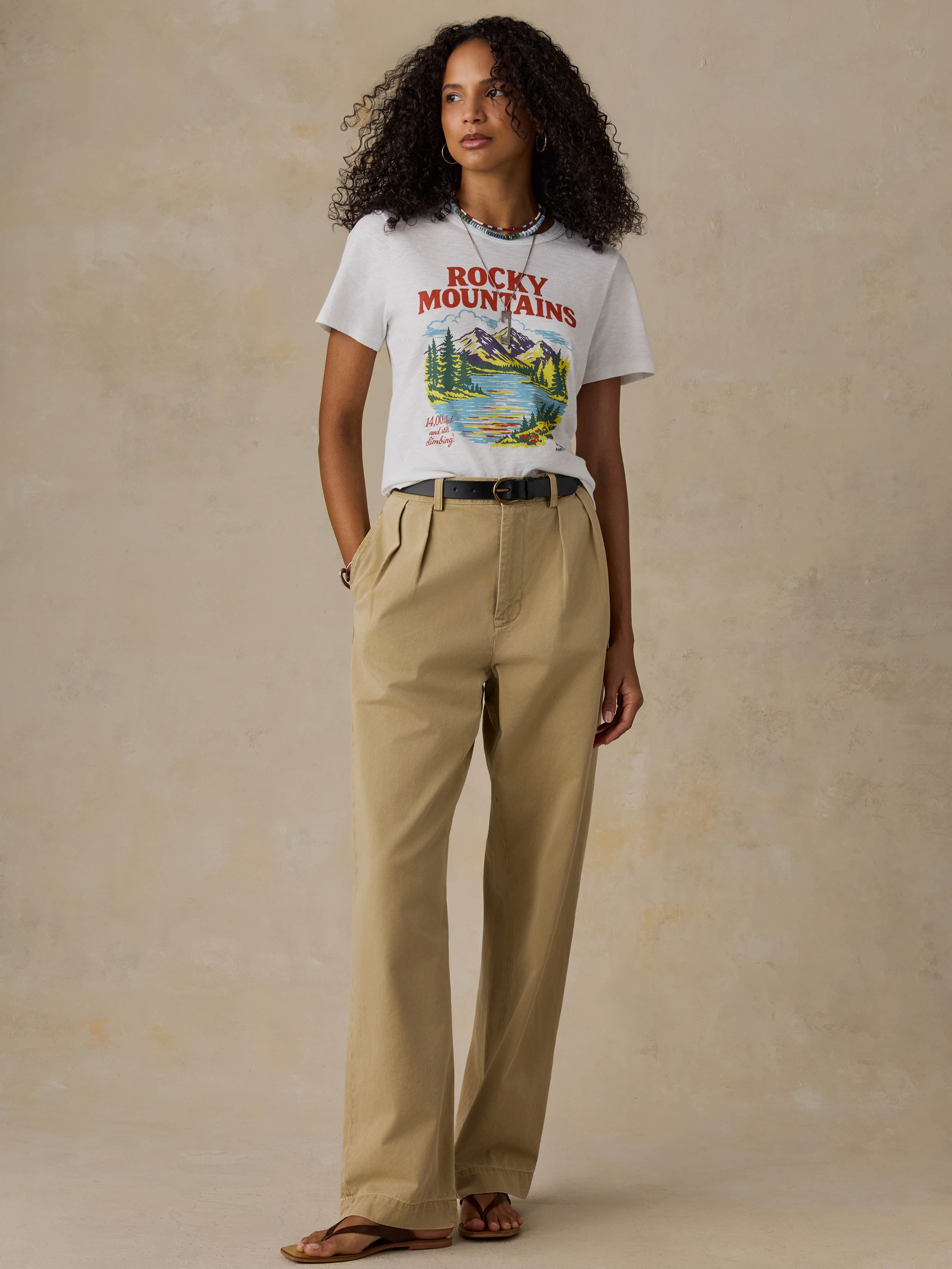 Woman wearing a white t-shirt with 'Rocky Mountains' design on a beige background