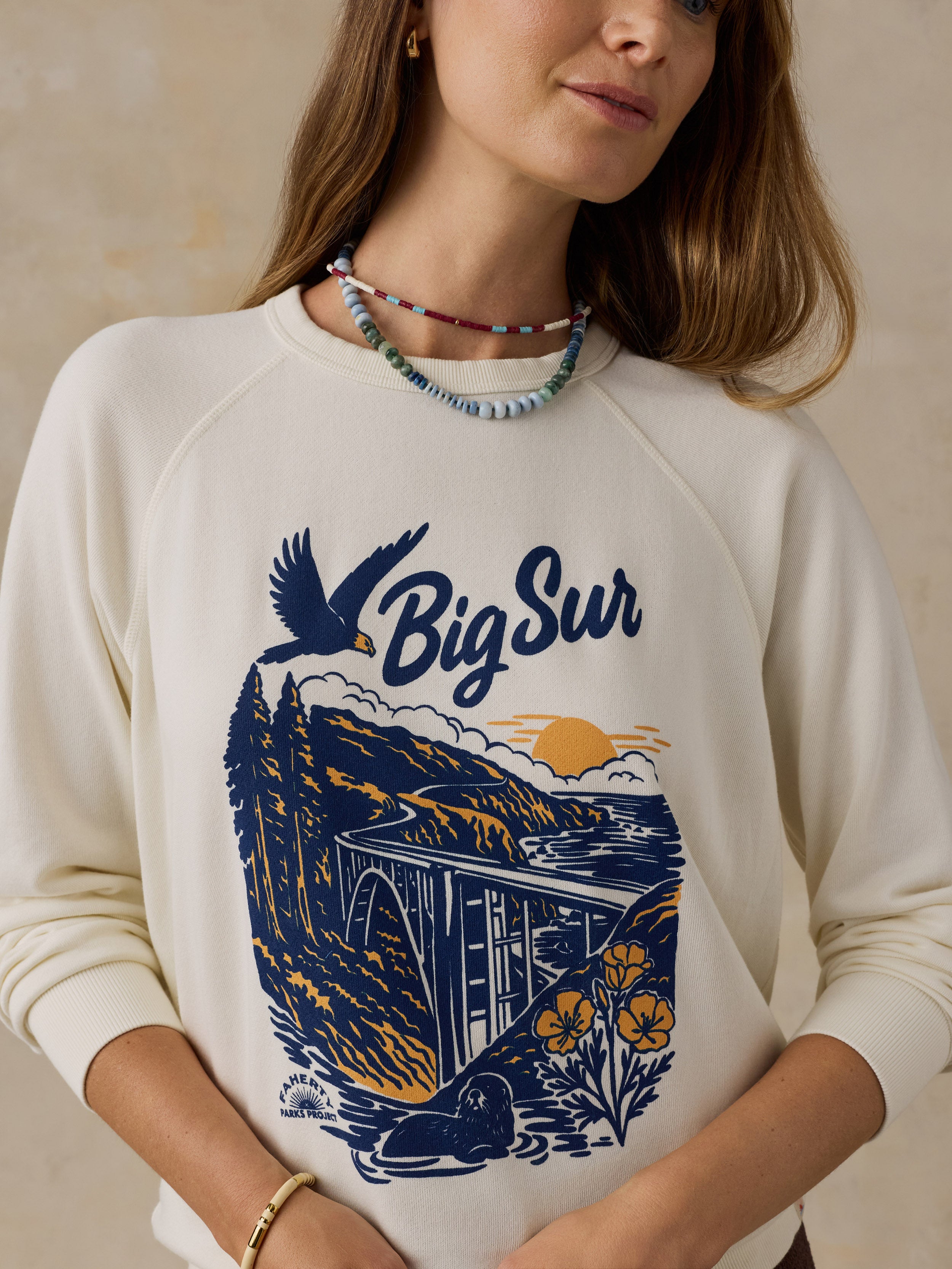 Woman wearing a Big Sur crewneck against a beige background