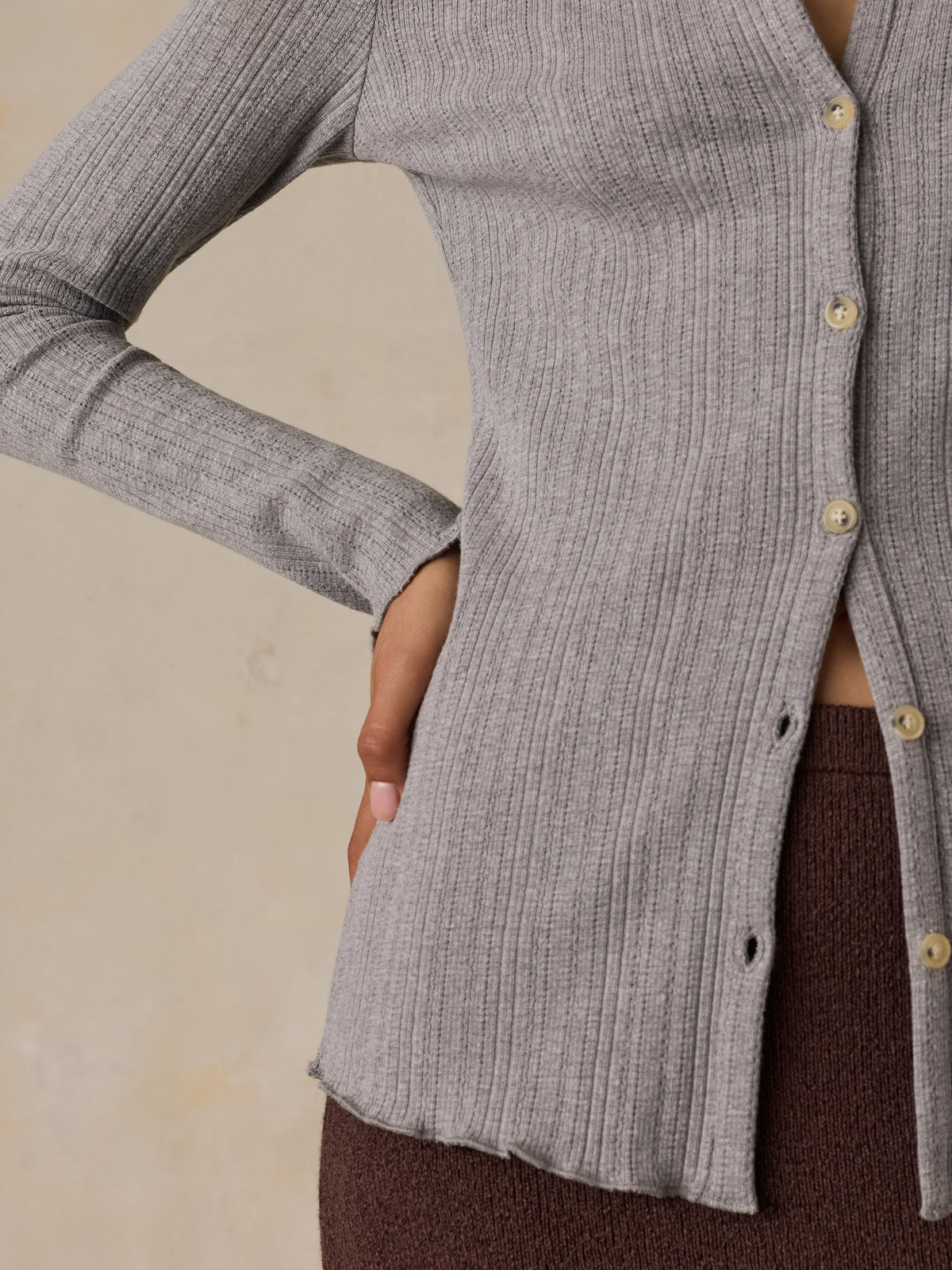 Close up of a woman wearing a grey cardigan and brown skirt, image 4 of 6