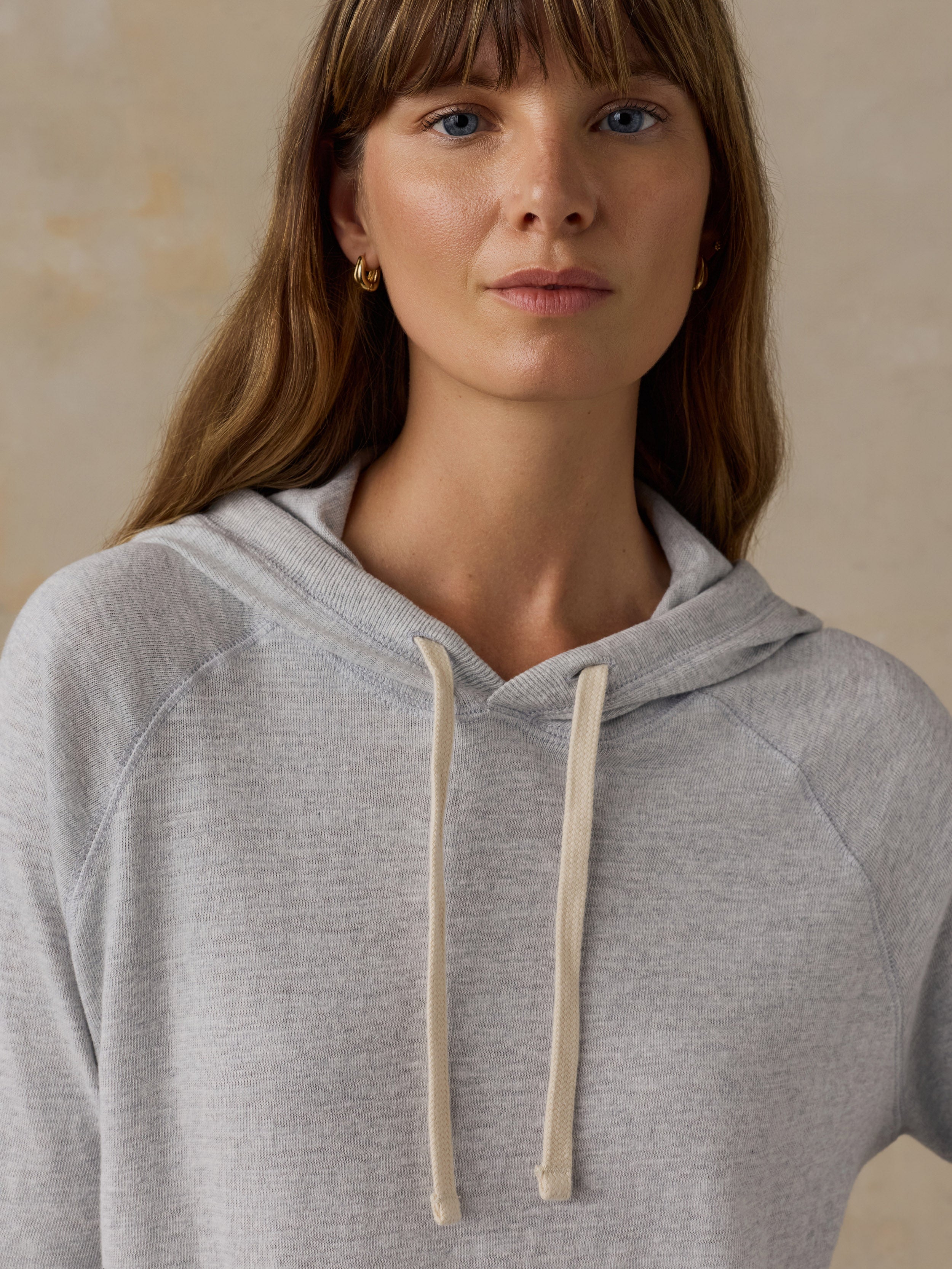 Woman wearing a grey sweatshirt against a beige background