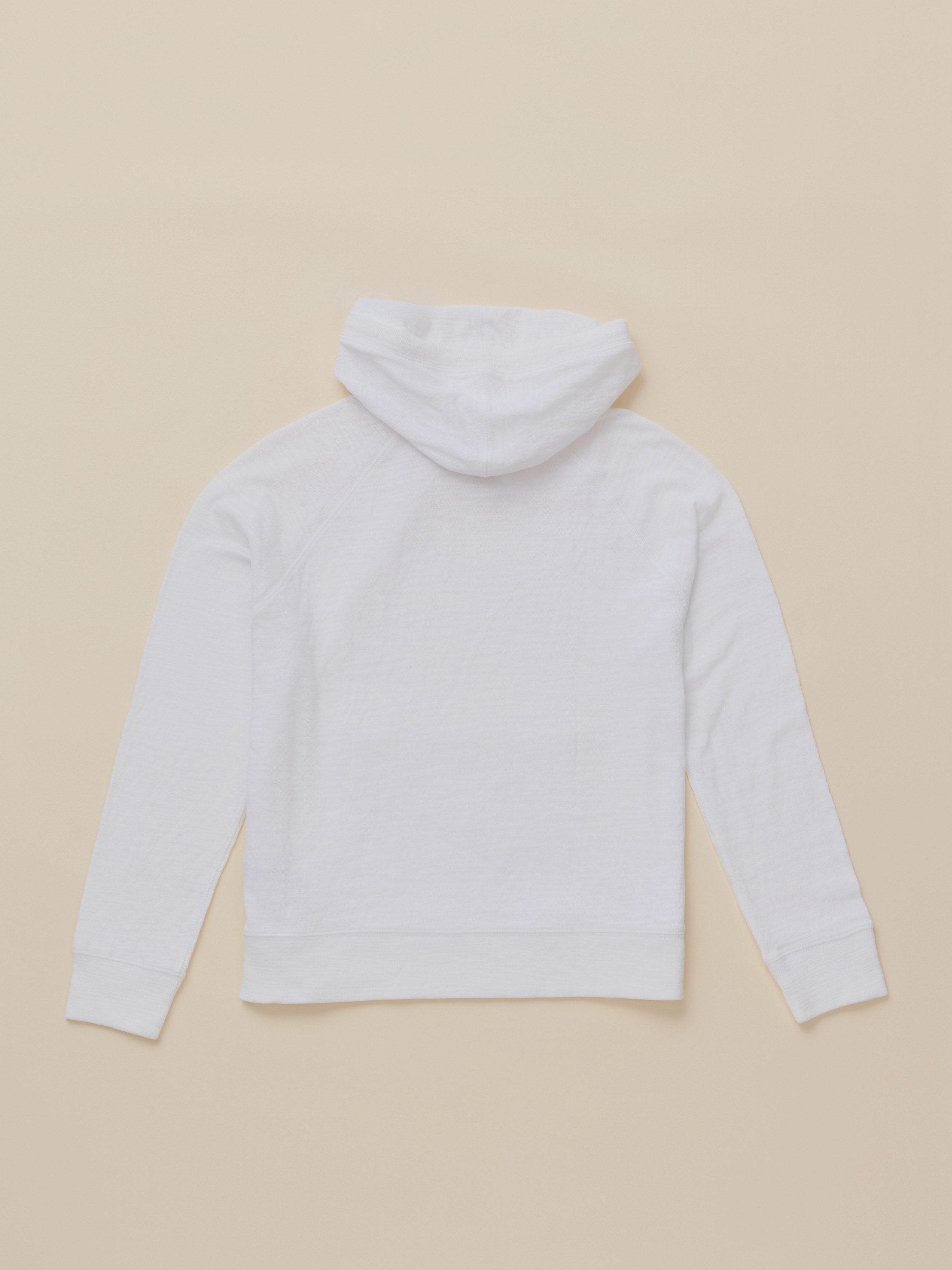 A white long-sleeve hoodie shown from the back, laid flat on a solid beige background.